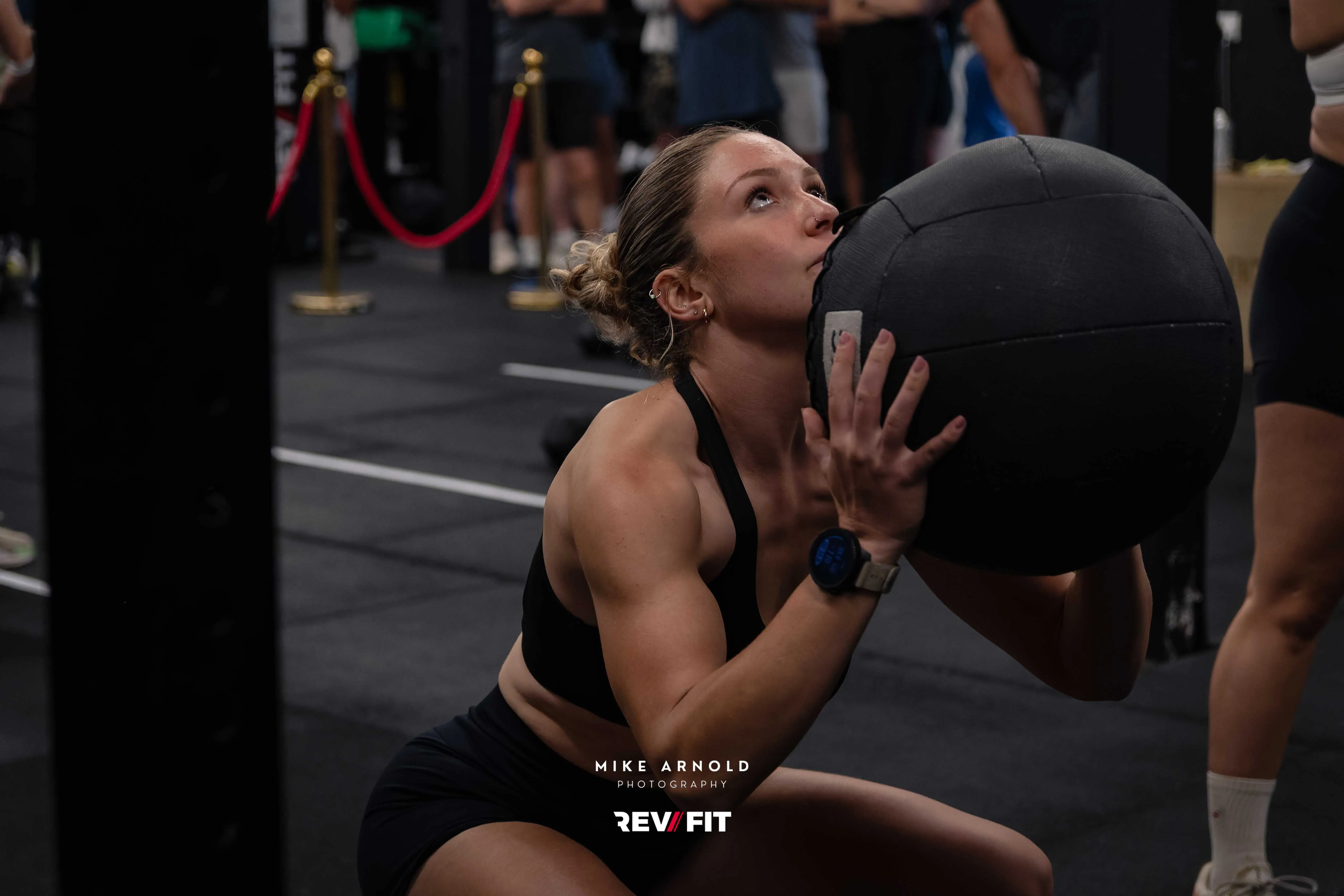 A competitor catching a wall ball mid-rep under the gym lights.