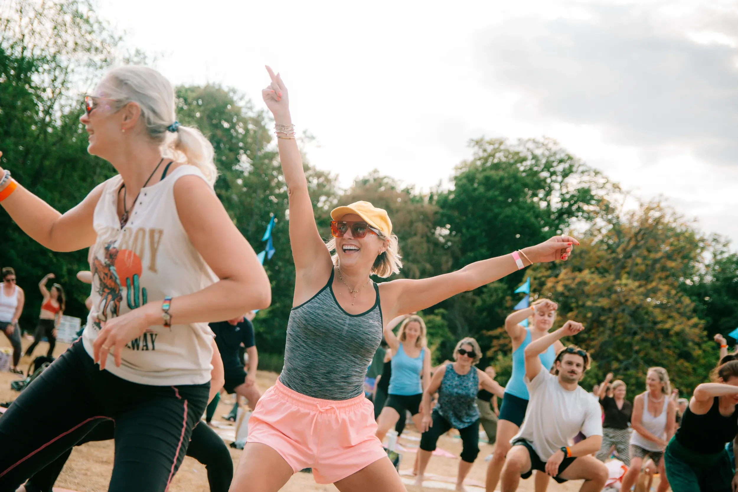 A woman in a yellow cap dancing with one arm pointed at the sky, the whole field moving behind her.