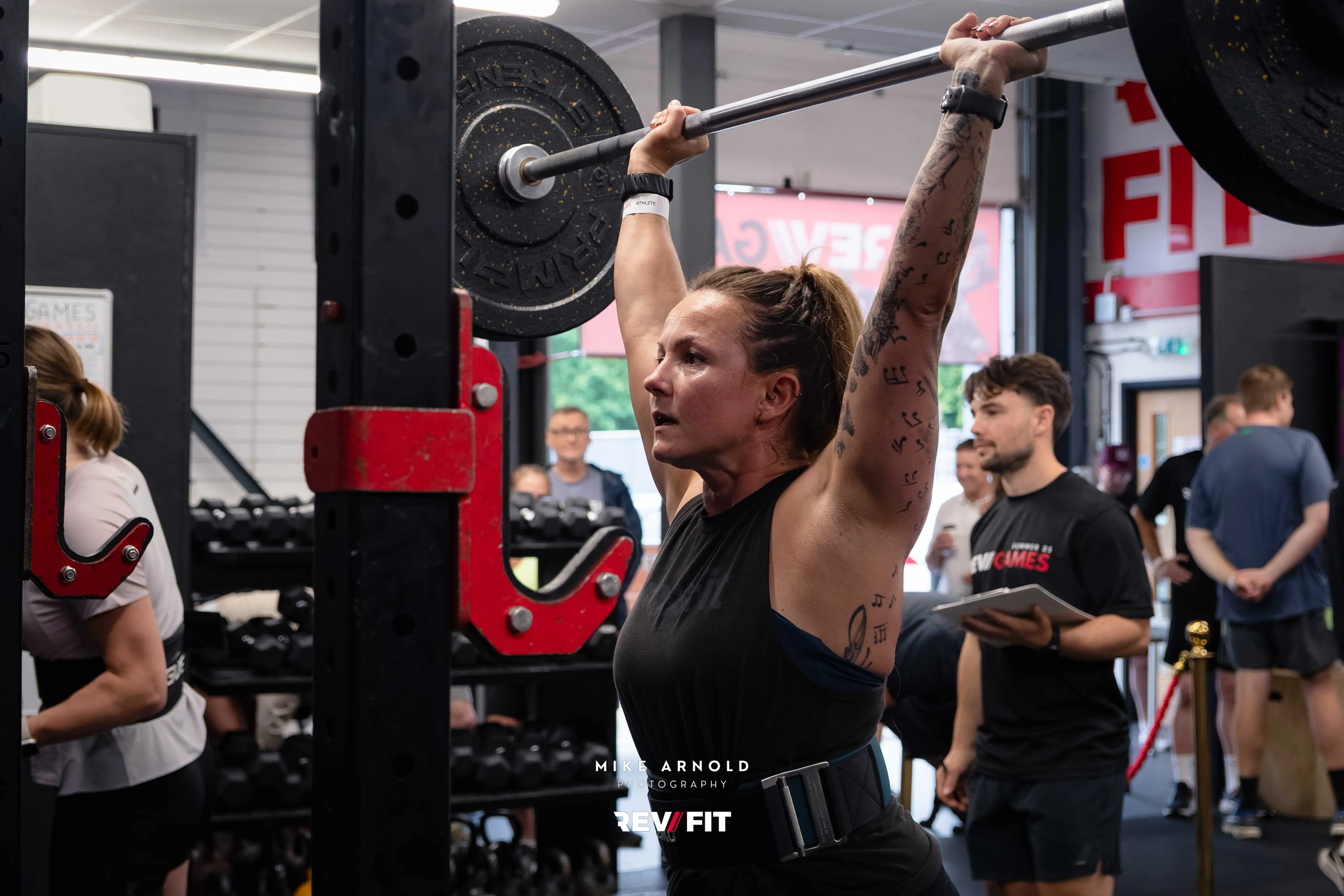 A competitor driving a barbell overhead mid push press.