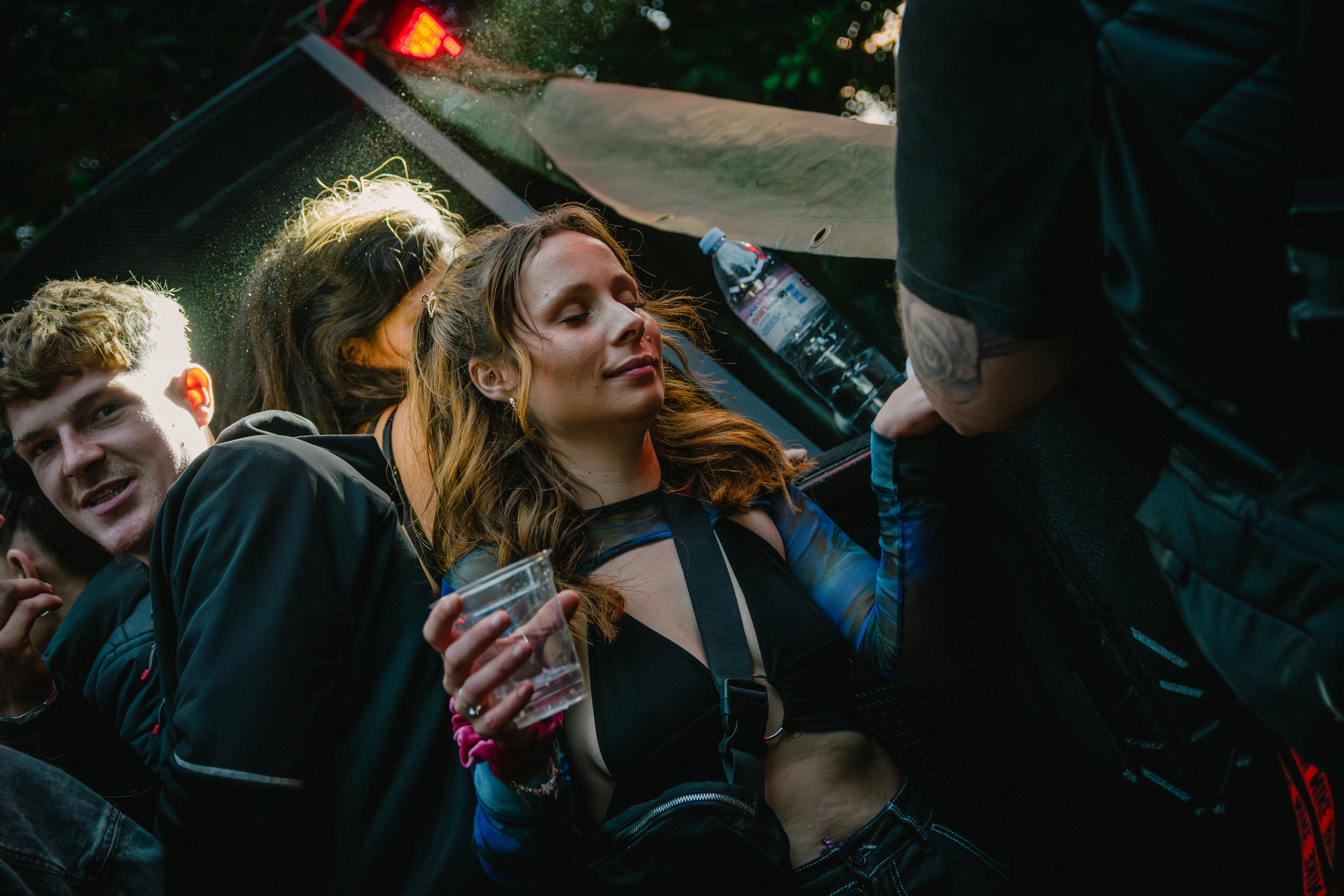 Two people close together holding drinks in a dark club, lit by warm stage light.