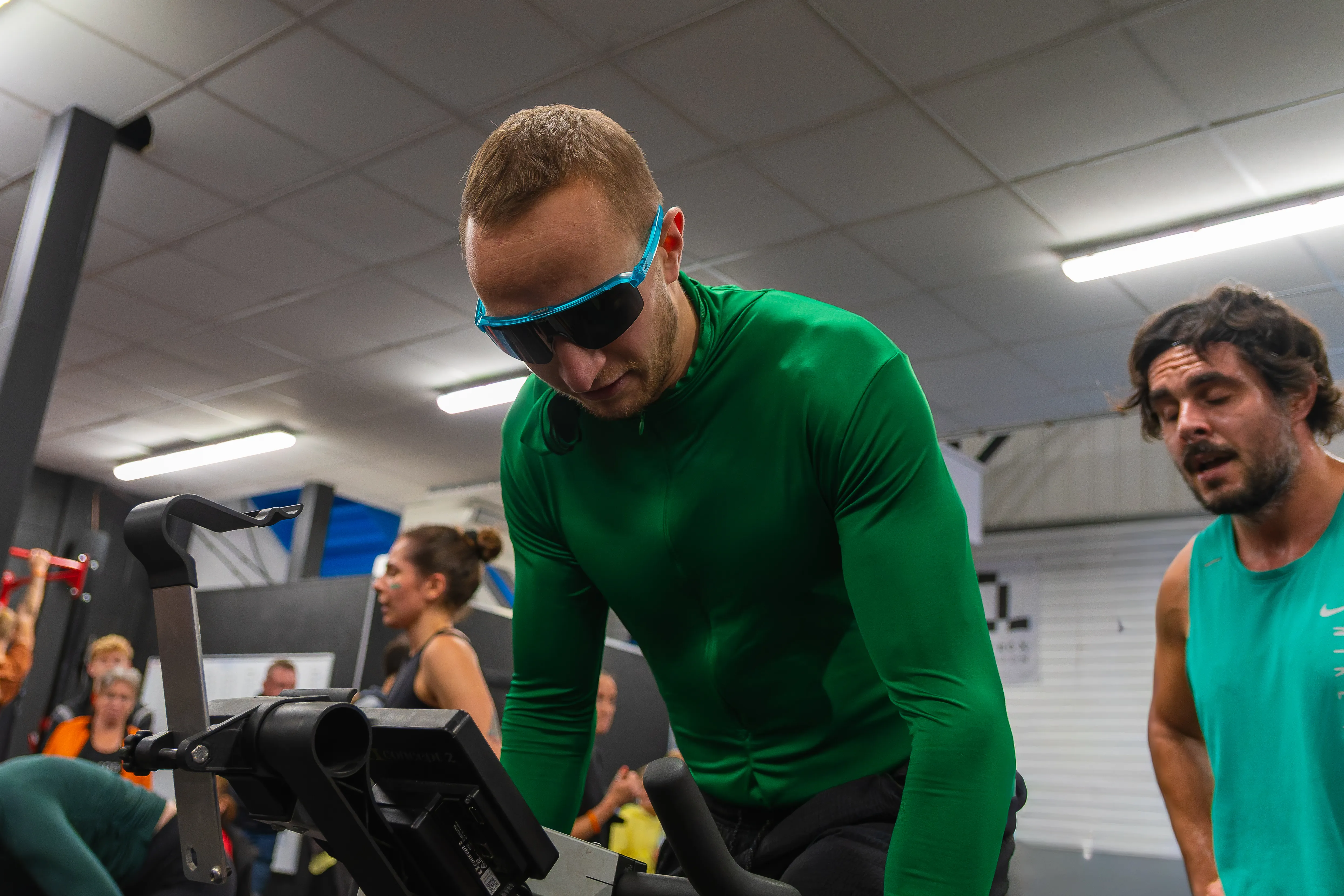 A competitor in a green top and sports sunglasses between efforts.