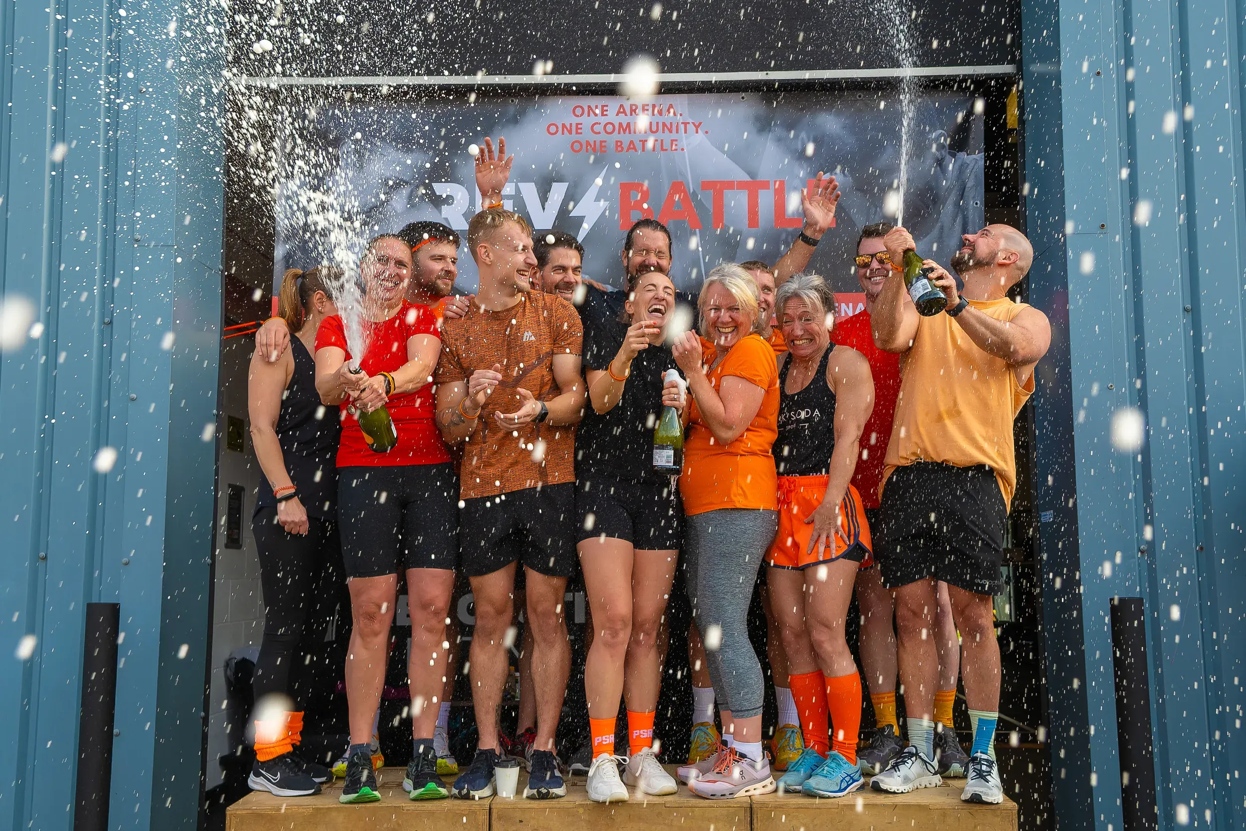 A team spraying champagne in celebration on a podium after a fitness competition.