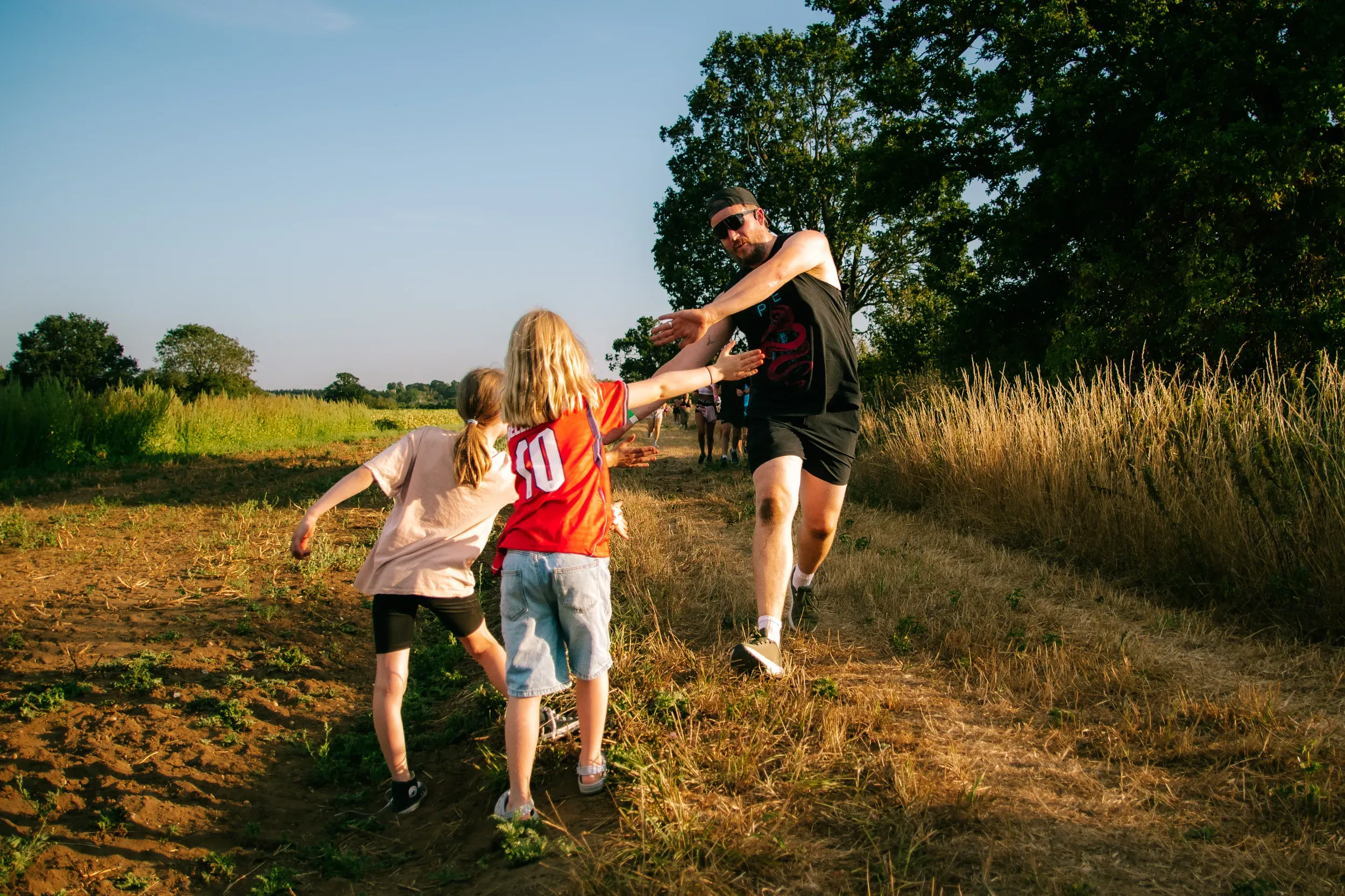 Two children stretching out to high-five a runner as he sprints past them on the field path.