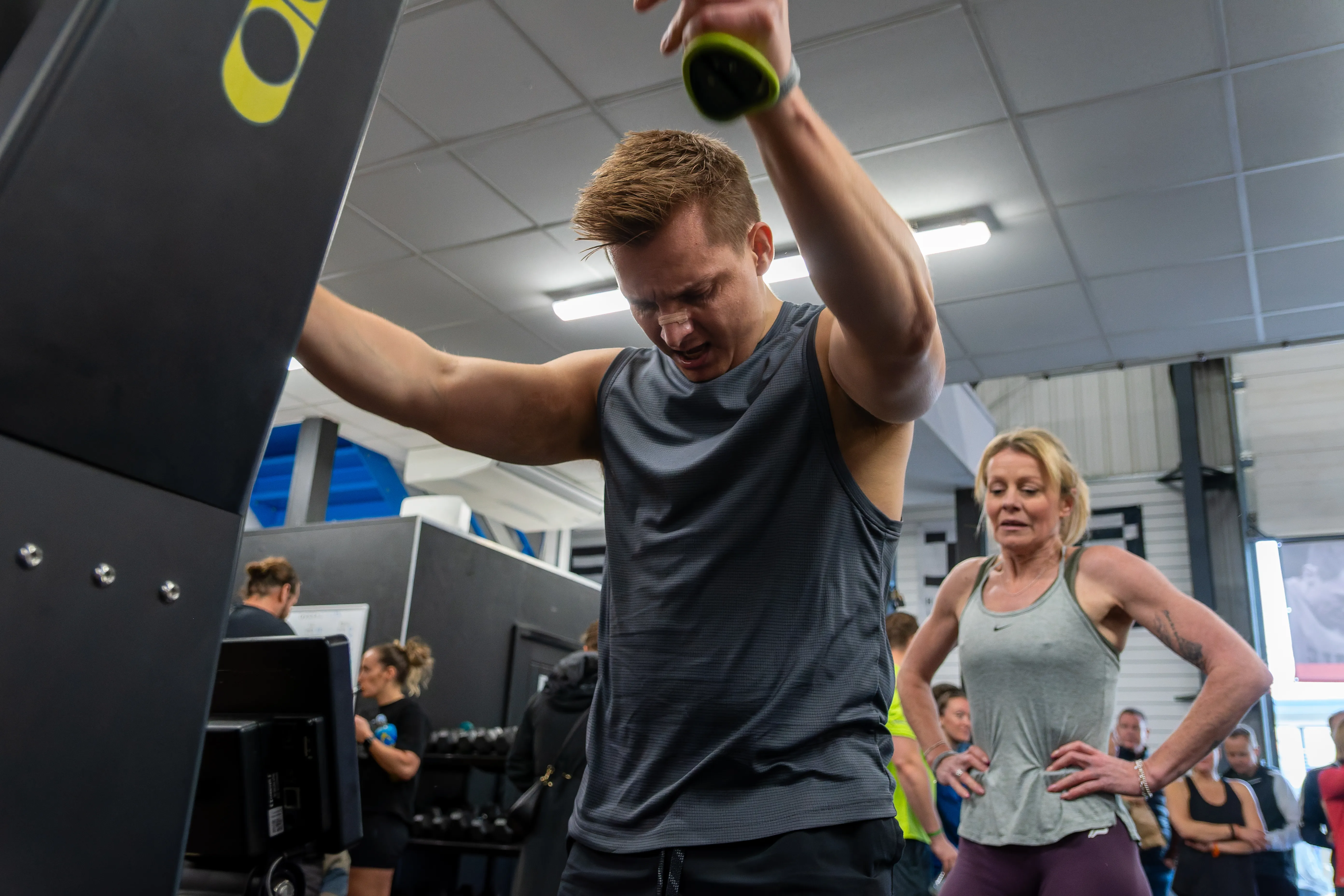 A competitor shaking out his arms between stations as a teammate looks on.