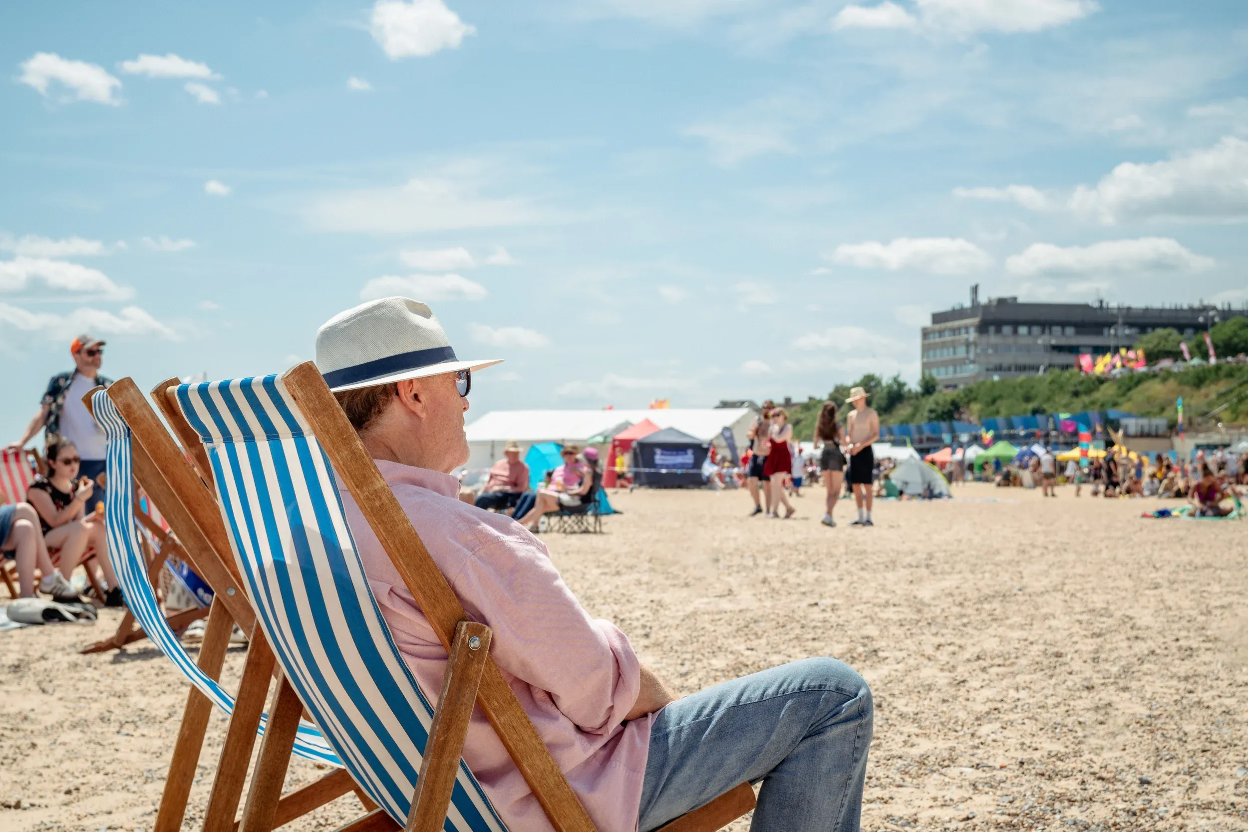 A man in a panama hat watching the beach from a striped deckchair at First Light Festival.