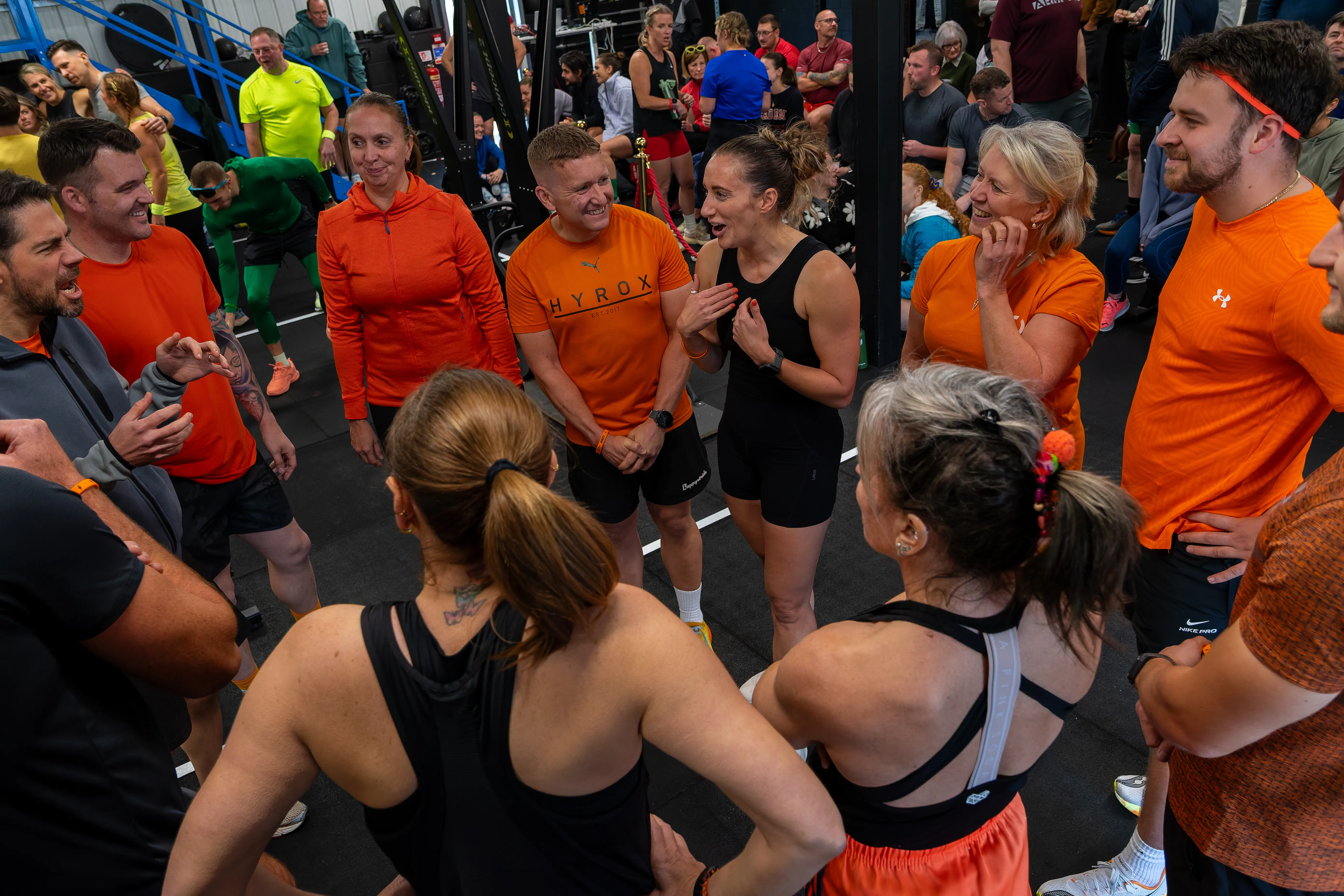 Teams in orange shirts huddled together between workouts.