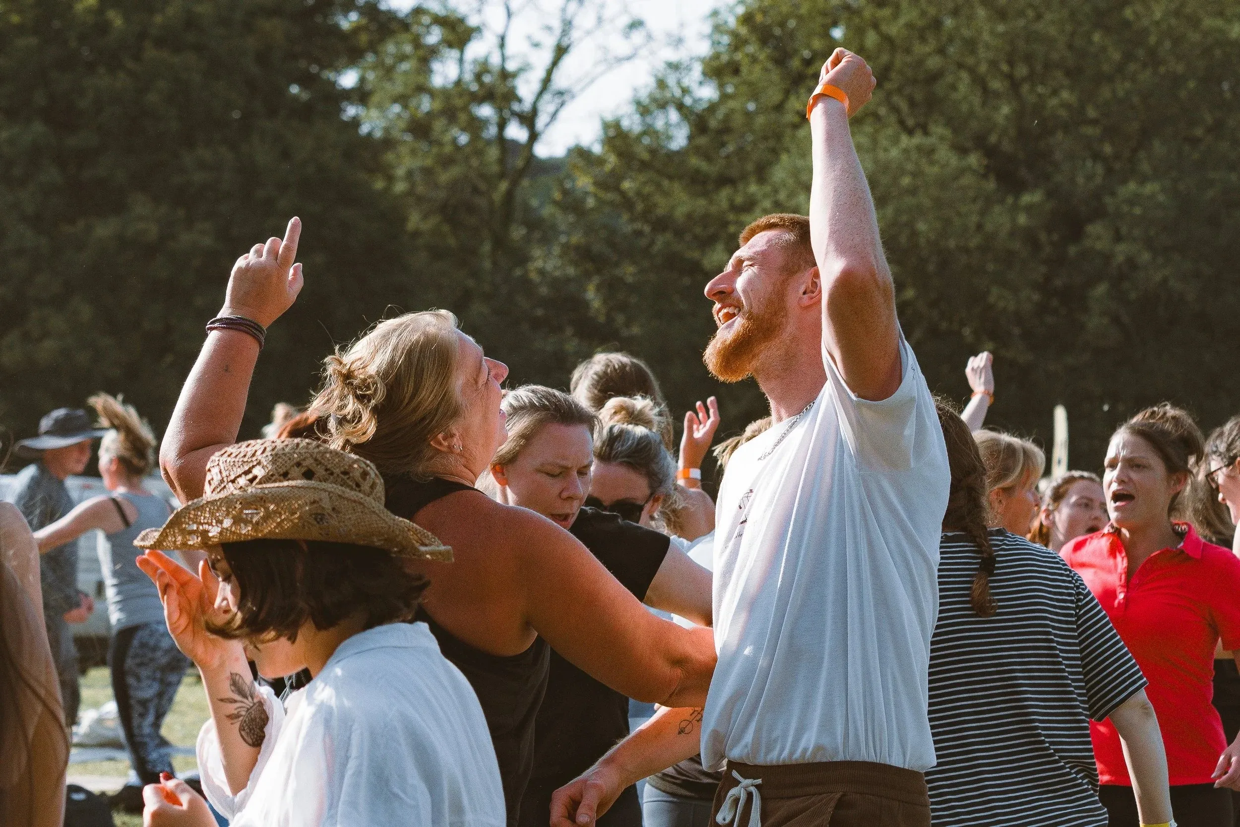 A red-haired man punching the air and cheering in a crowd of dancers at the festival.
