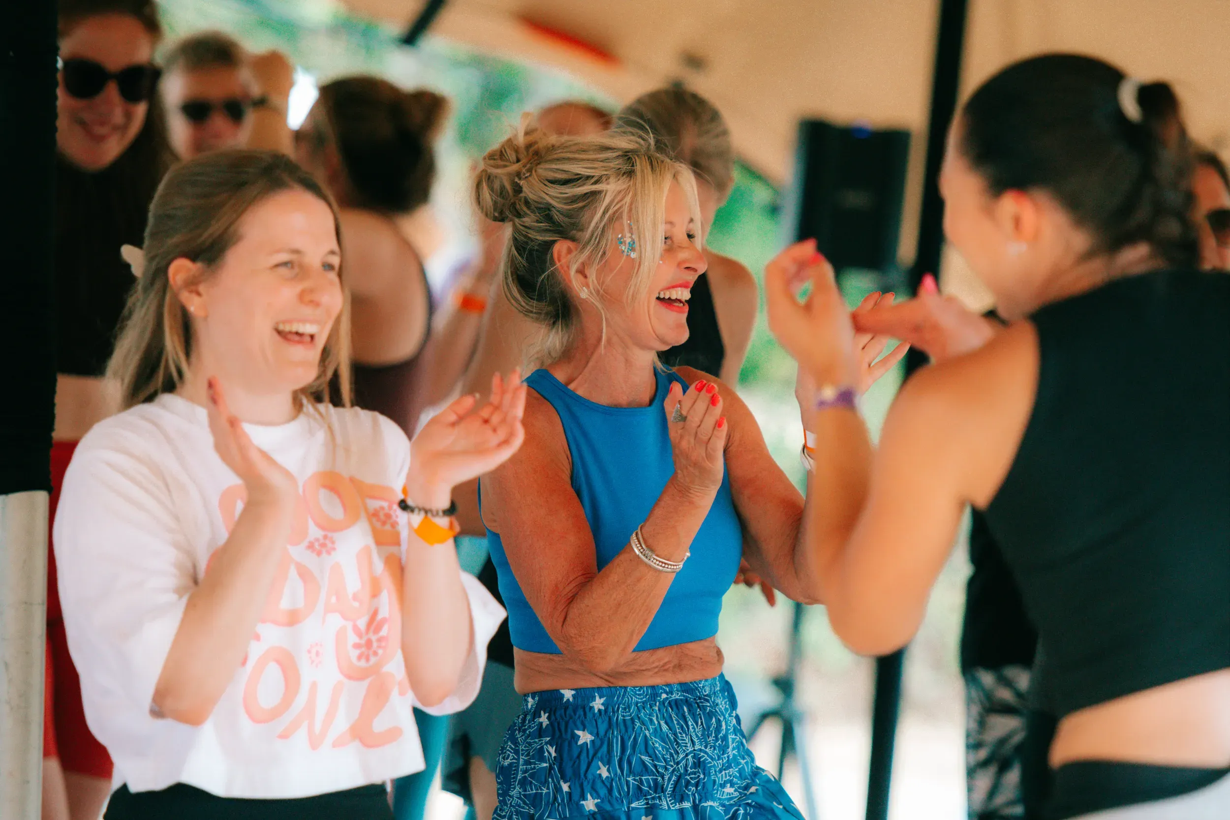 Two women laughing and clapping along together during a class under the canopy.