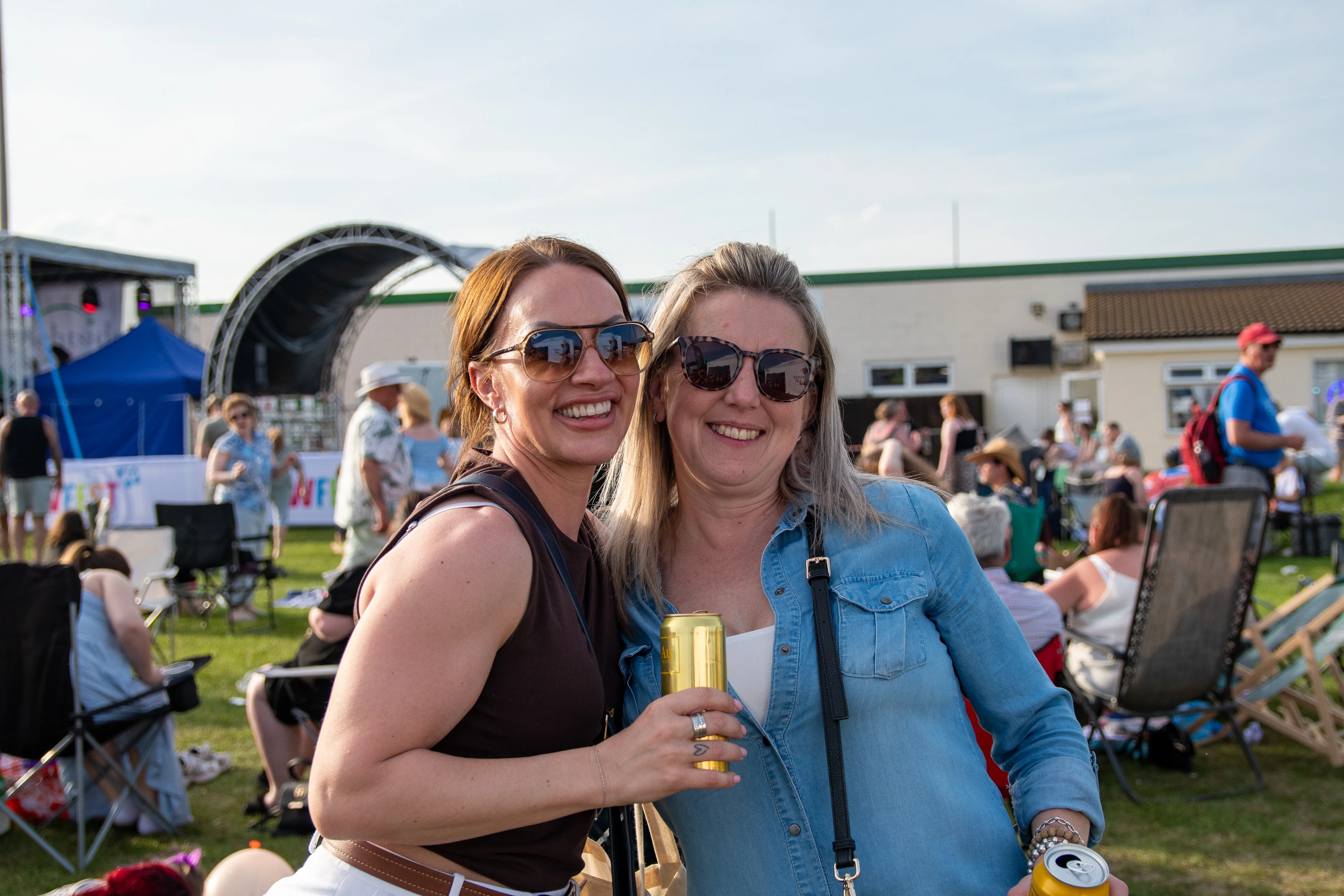 Two friends in sunglasses sharing a drink and a laugh.
