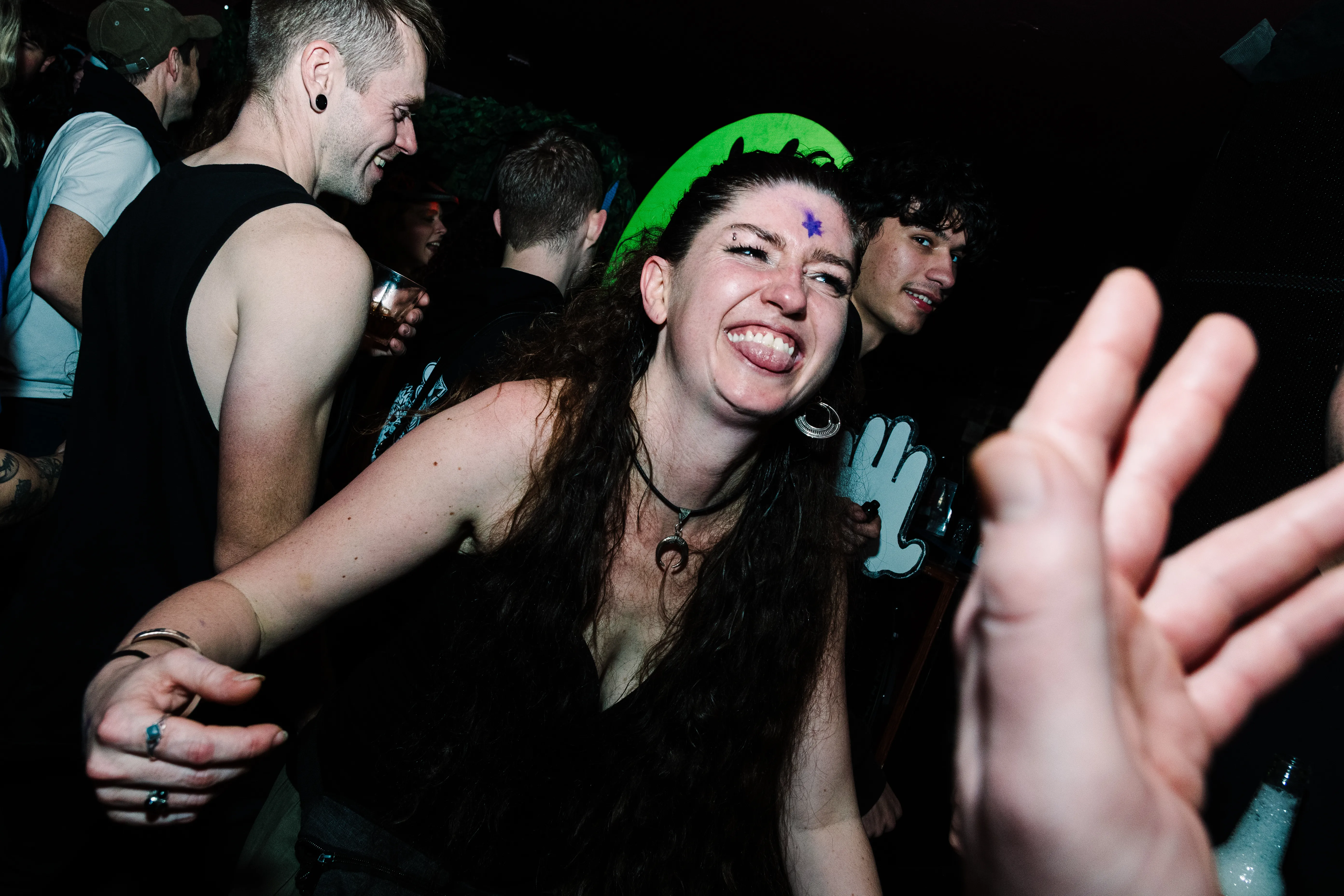 A dancer in a green cap reaching straight into the lens, the floor moving behind her.