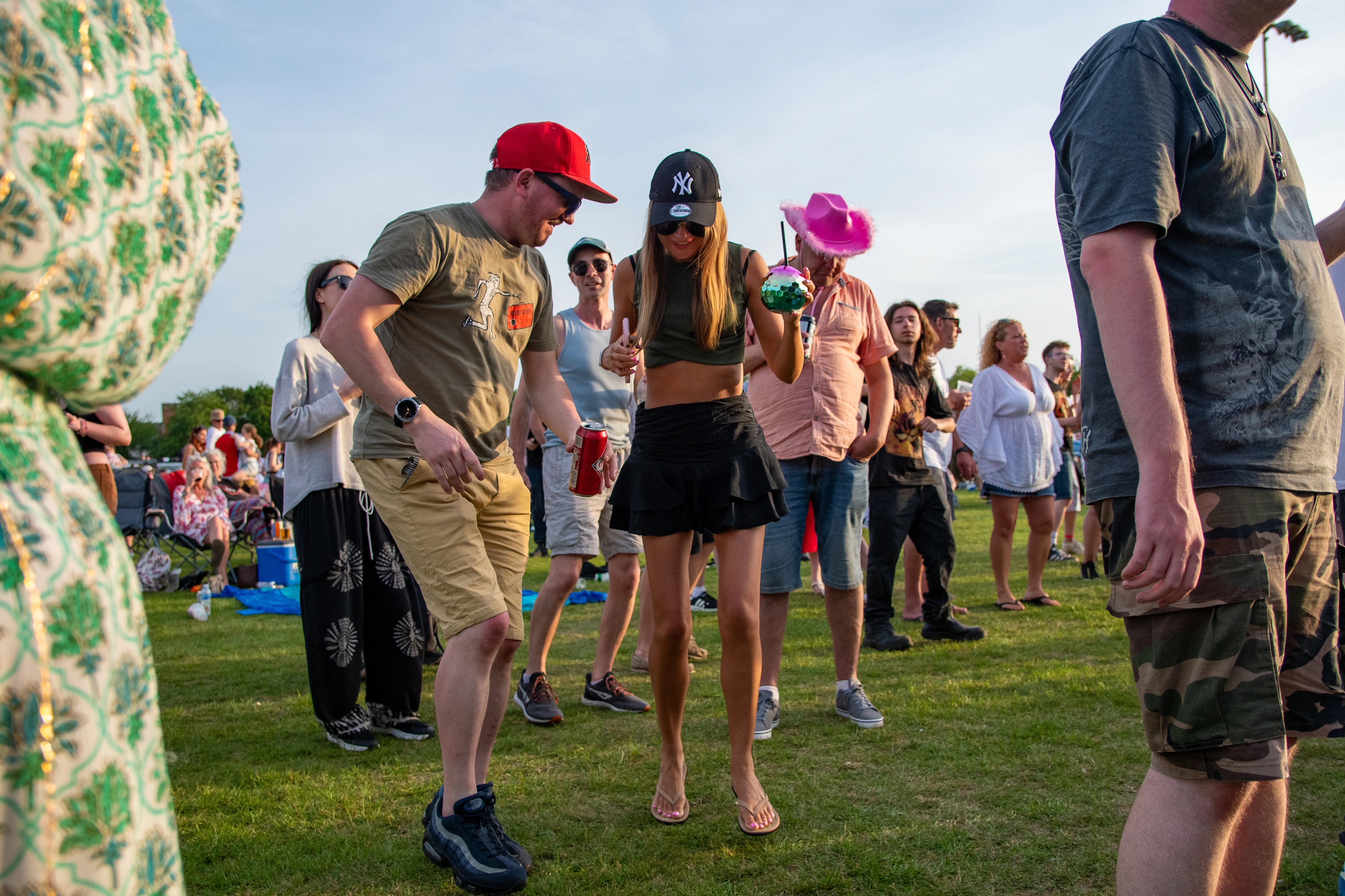 Friends in cowboy hats dancing together on the grass.