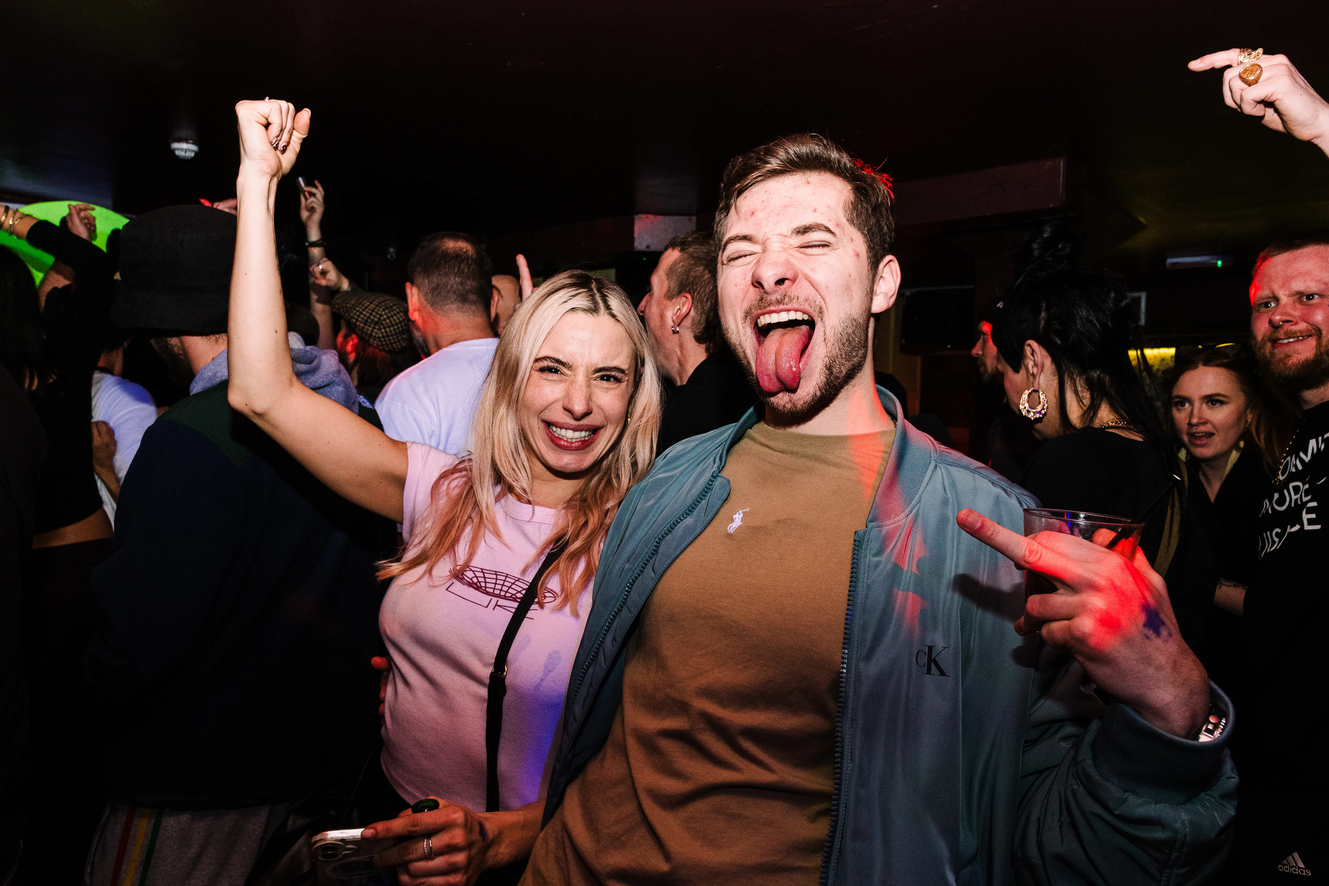 Two friends dancing with tongues out, caught in a burst of red light.