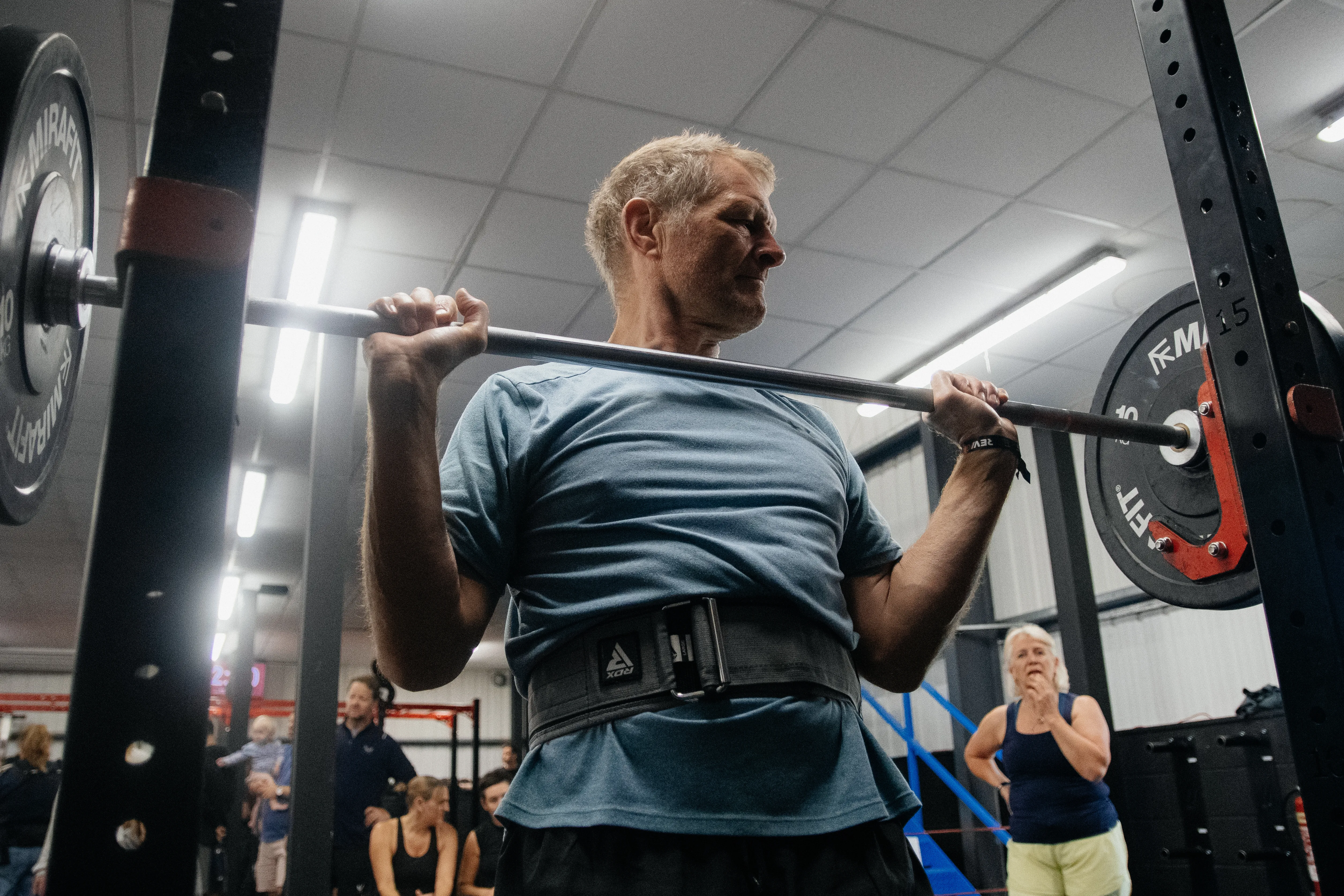 A competitor grinding through a heavy back squat as spectators watch.