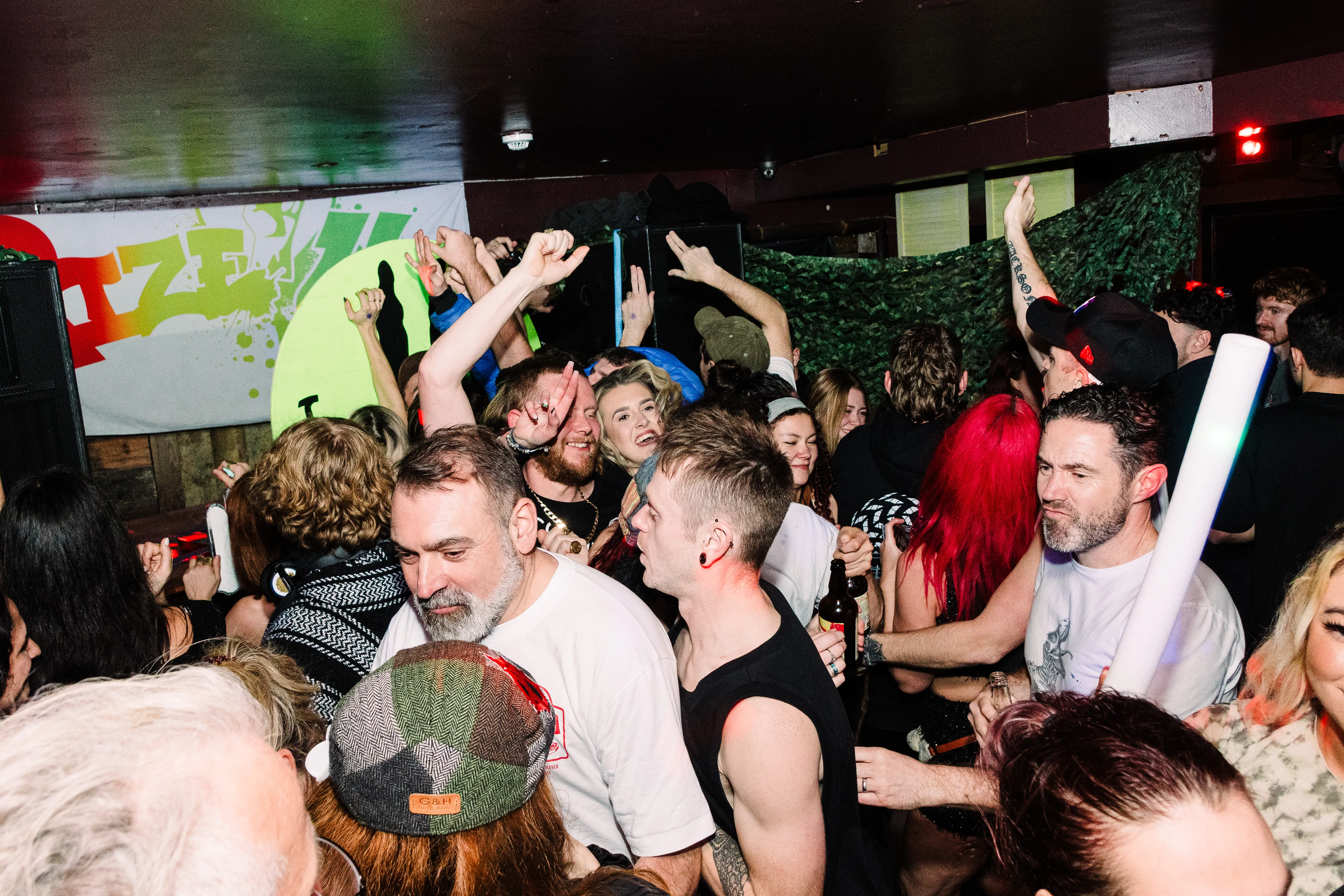 A wide view of the whole floor, hands and glowsticks in the air.