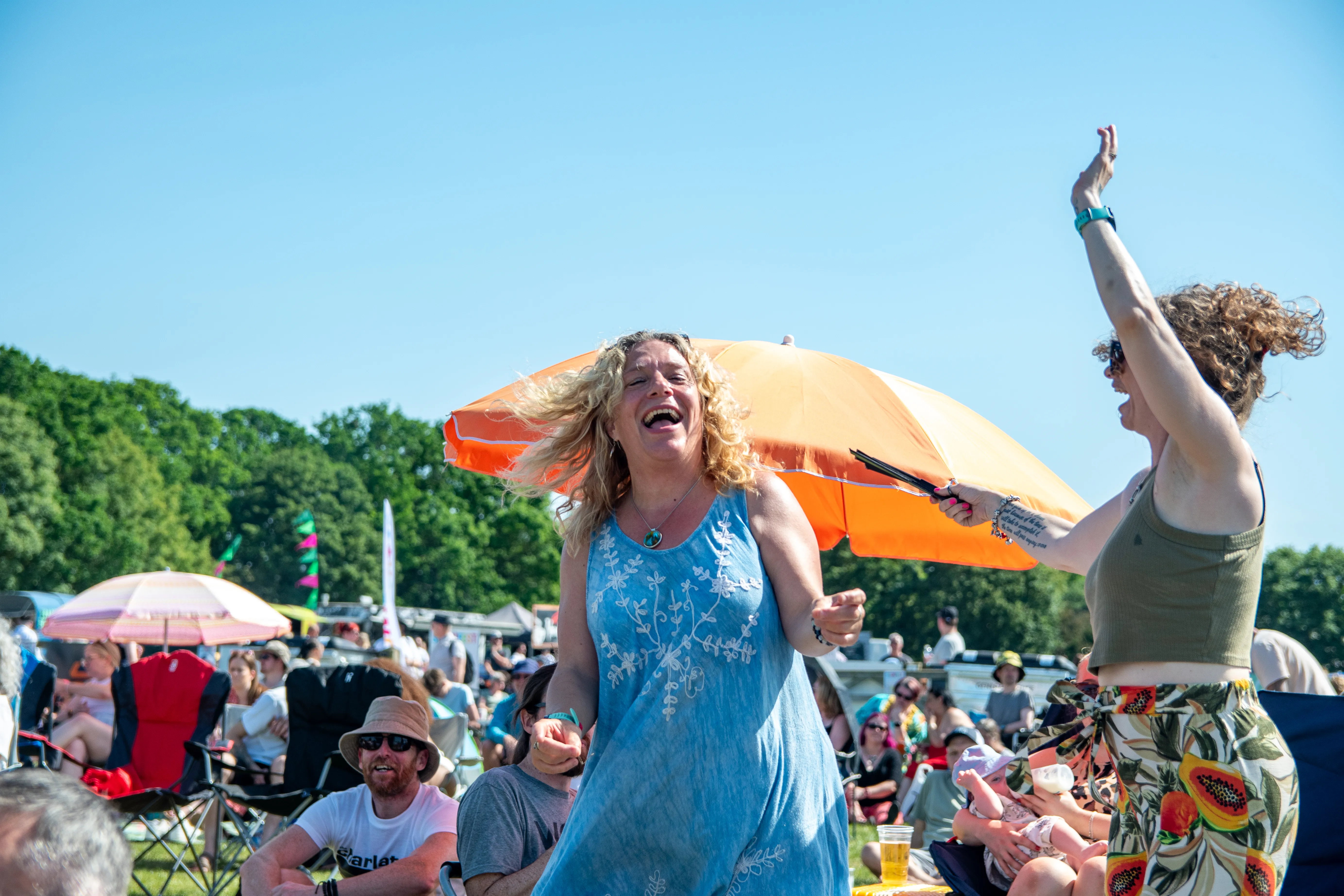 A woman mid-hair-flip dancing with a friend by the parasols.