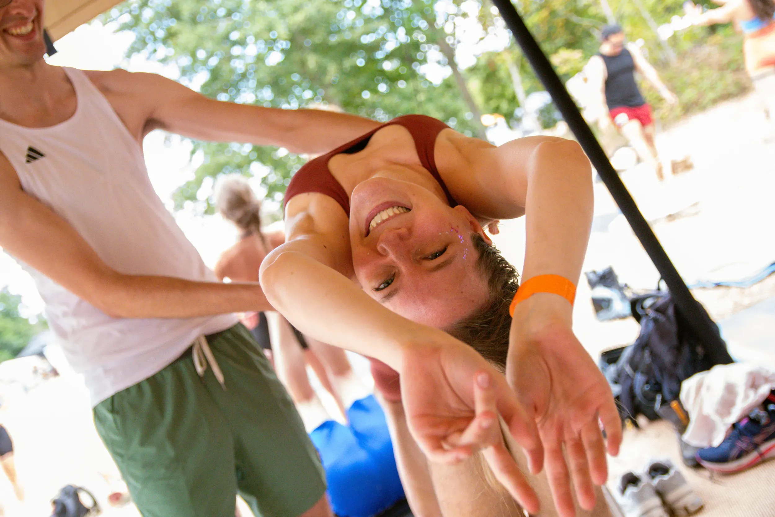 A woman laughing upside down mid-stretch, glitter on her face, her partner supporting her.