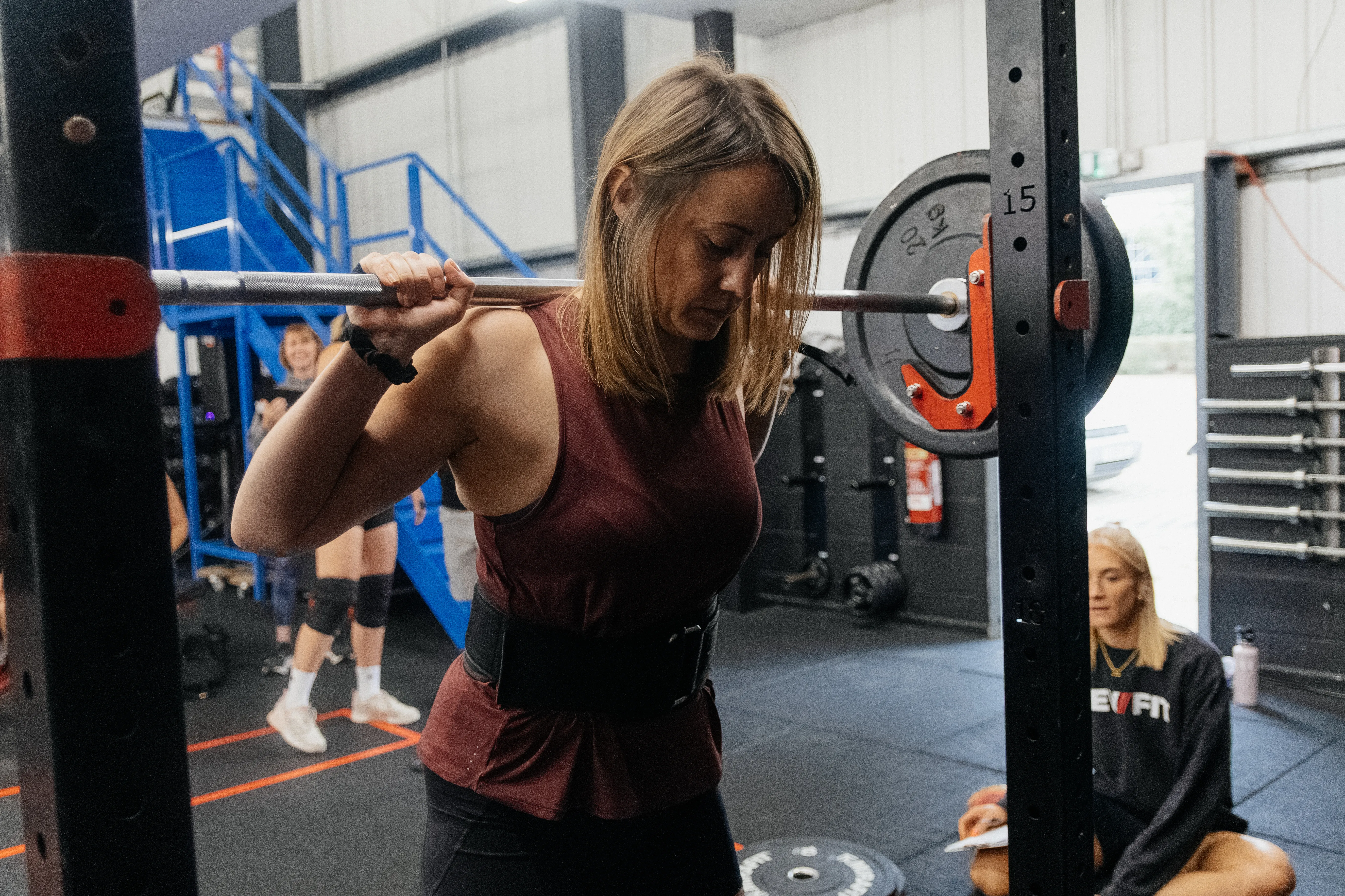 A competitor braced with the bar across her back.