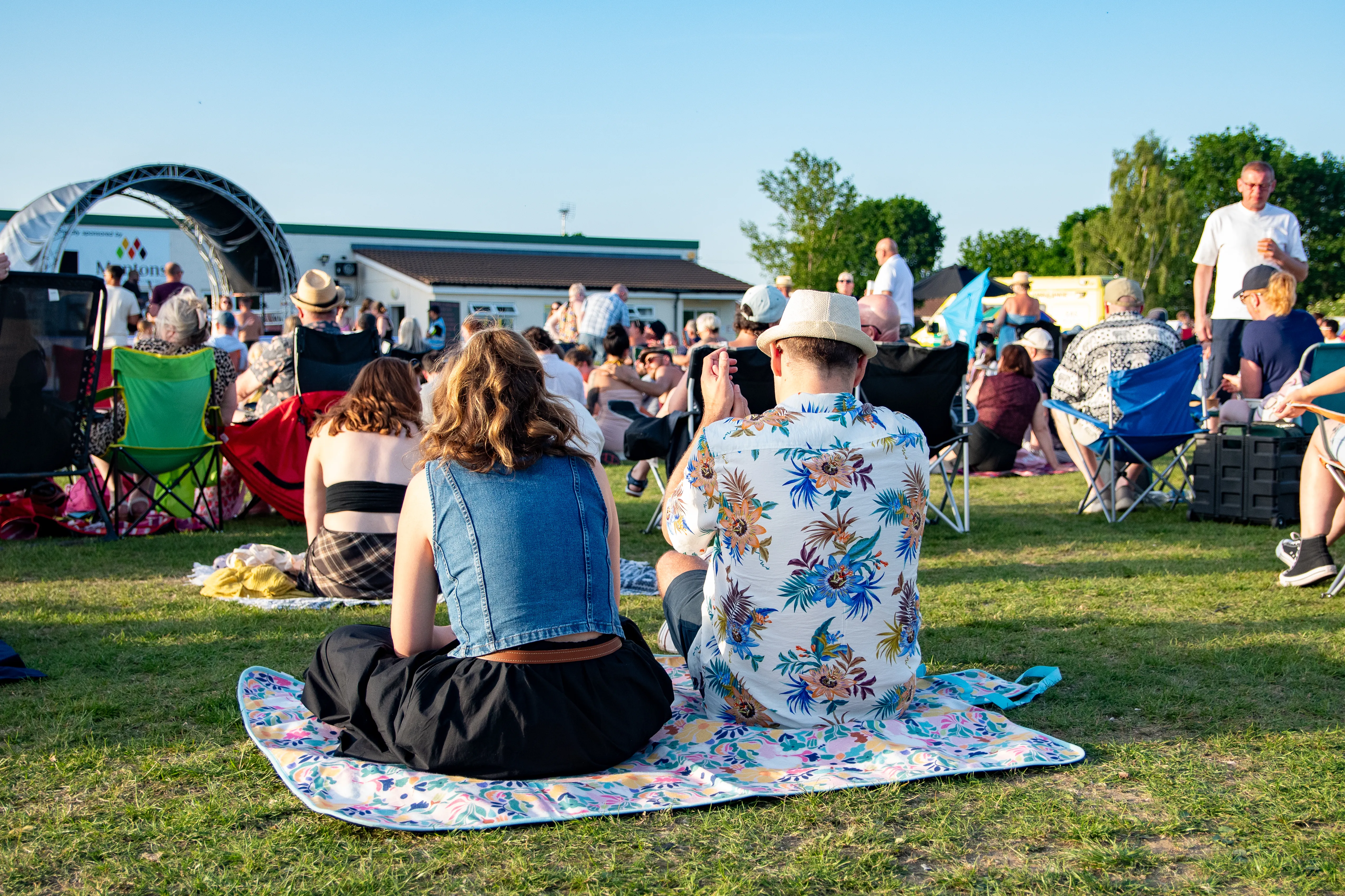 A couple sat on a picnic blanket watching the stage.