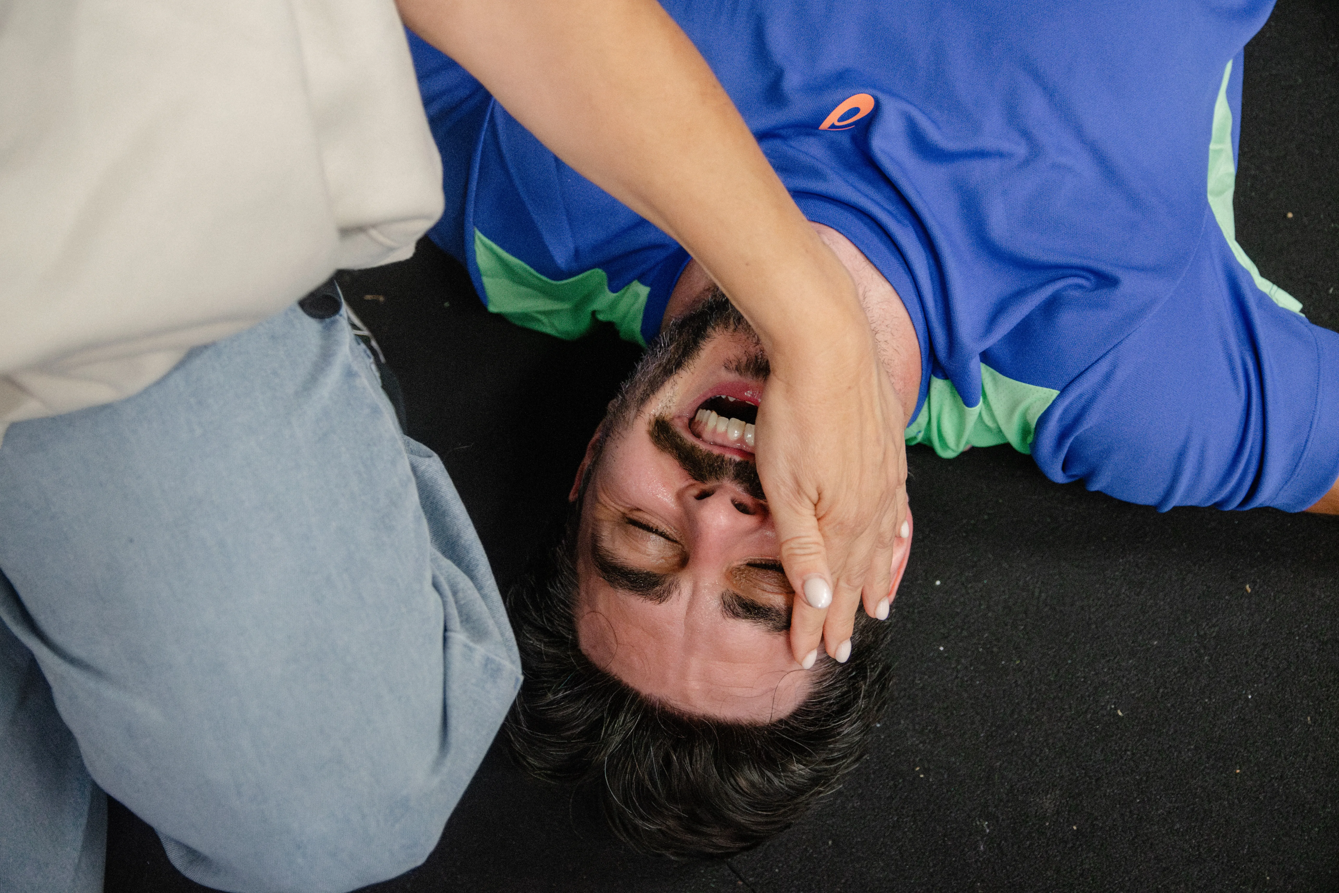 A competitor flat on the floor after a finish, hand over his face.