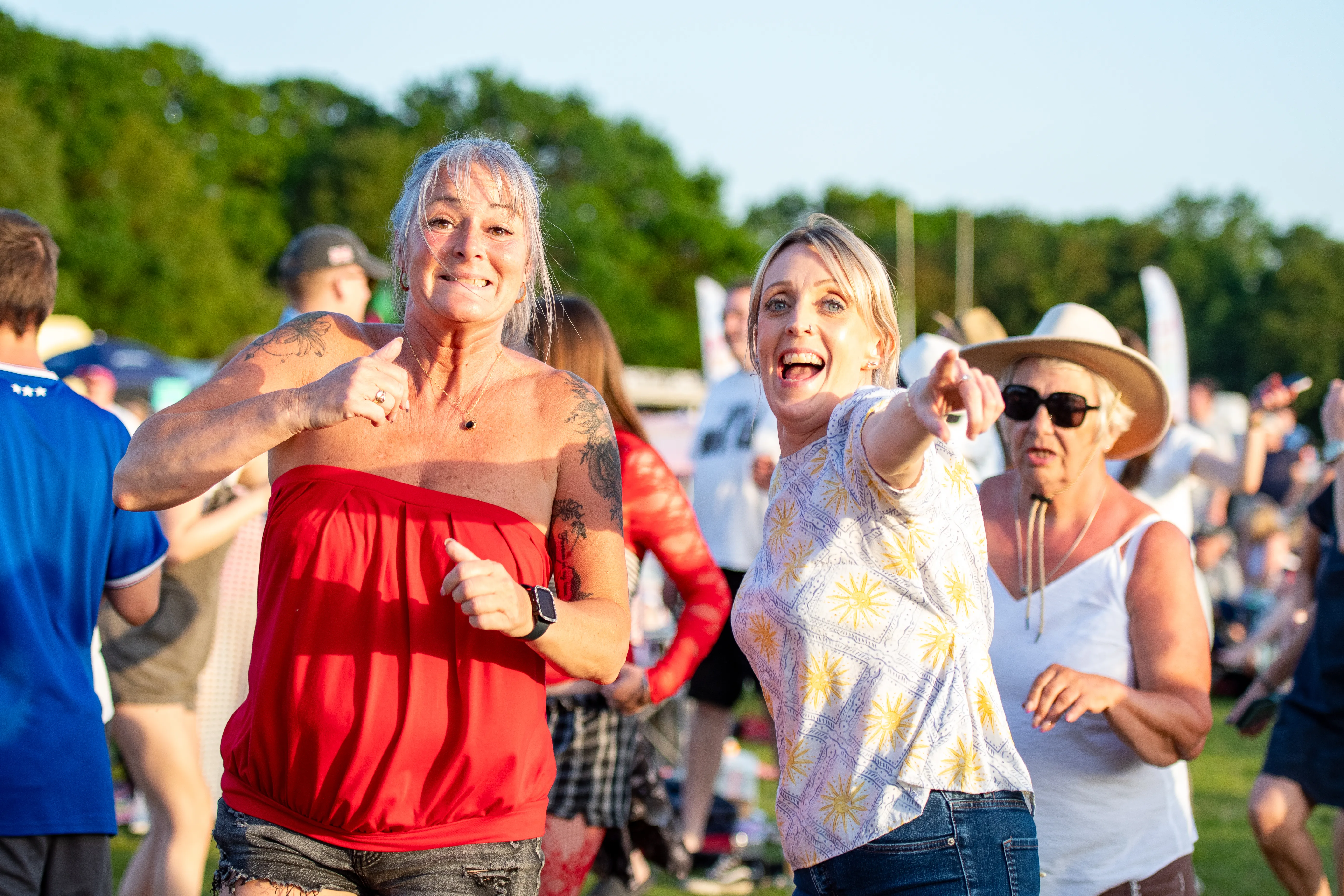 Three women pointing and singing along mid-set.