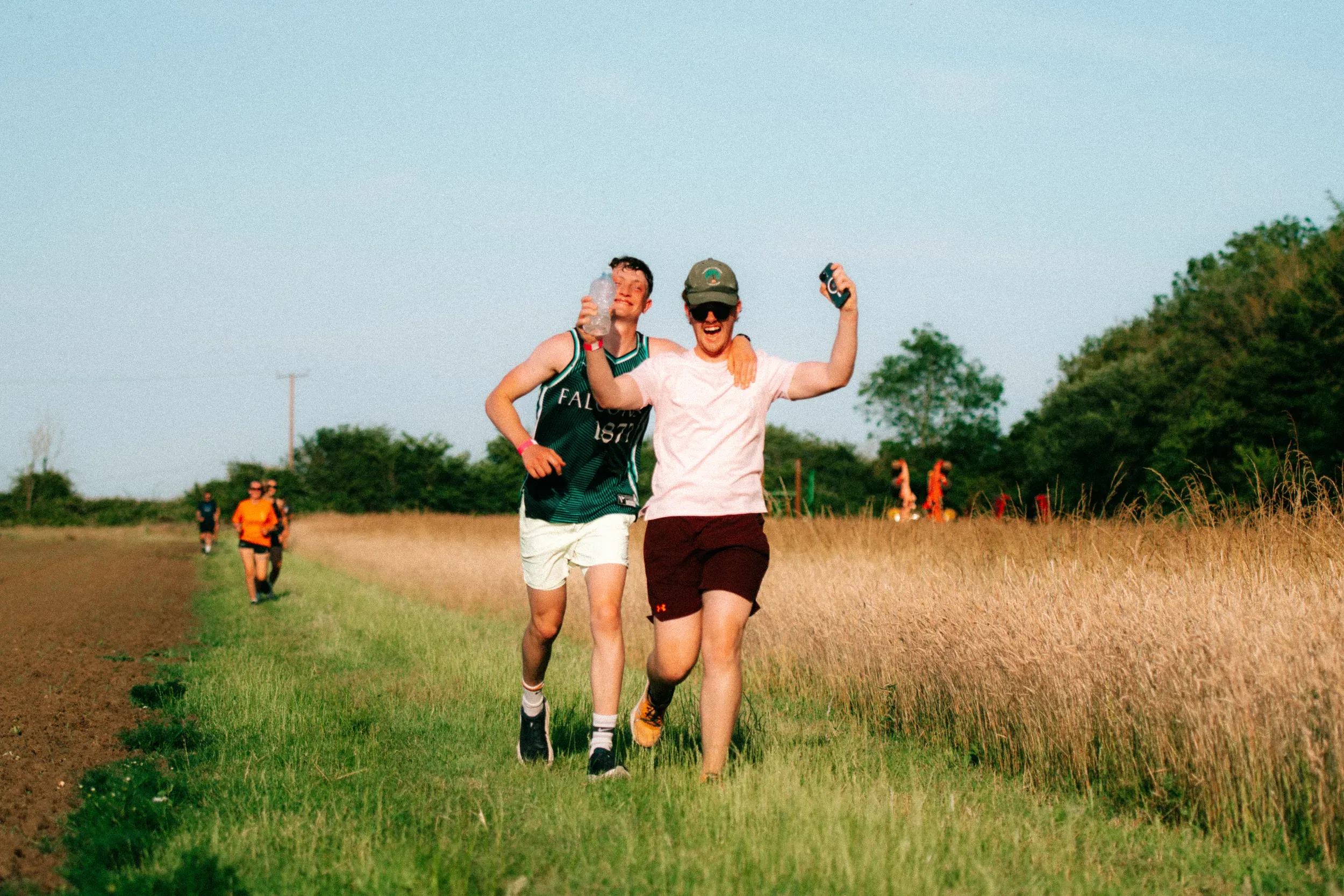 One runner with his arm slung round another's shoulders, both laughing as they come up the track together.