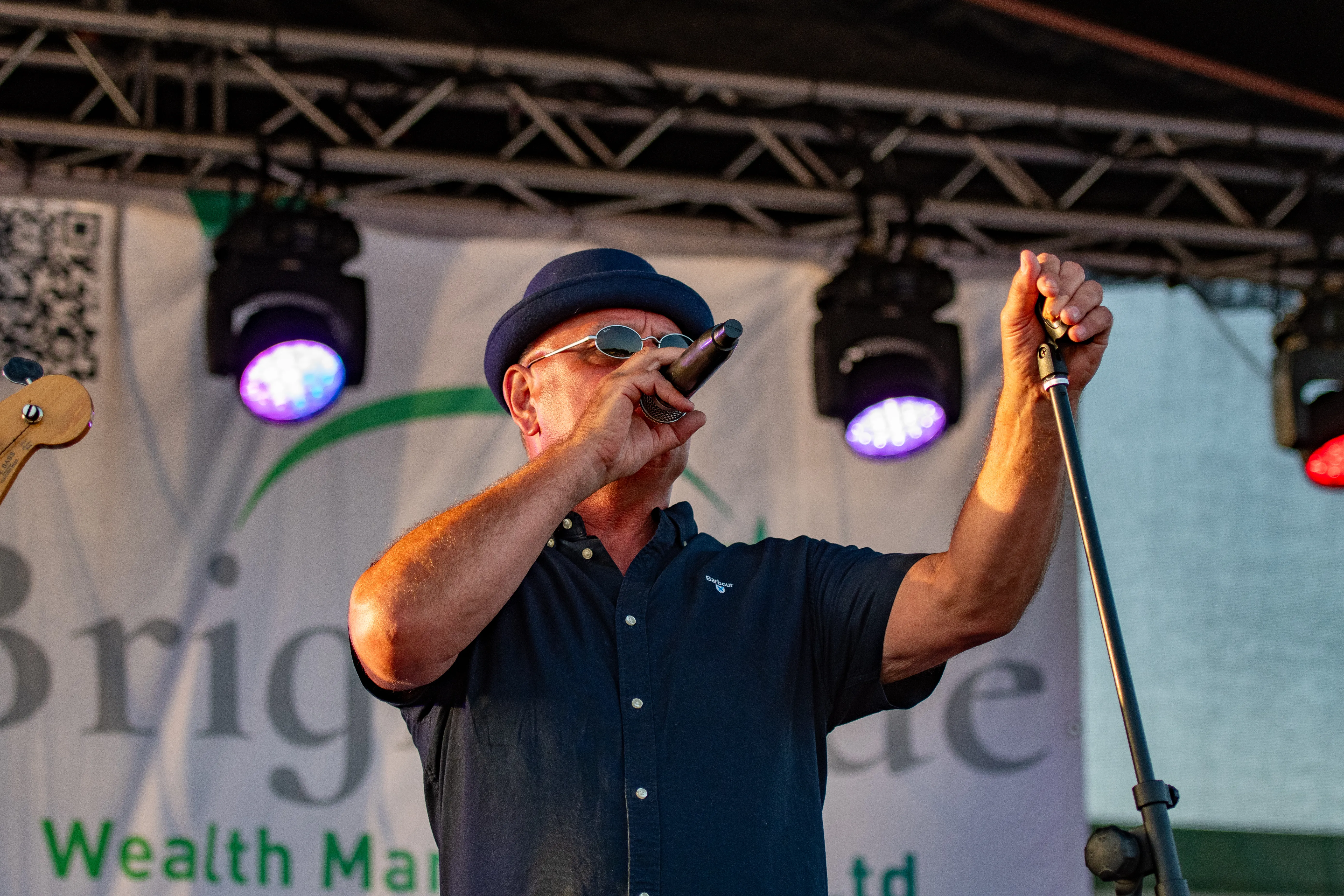 A singer performing on stage under purple lights.