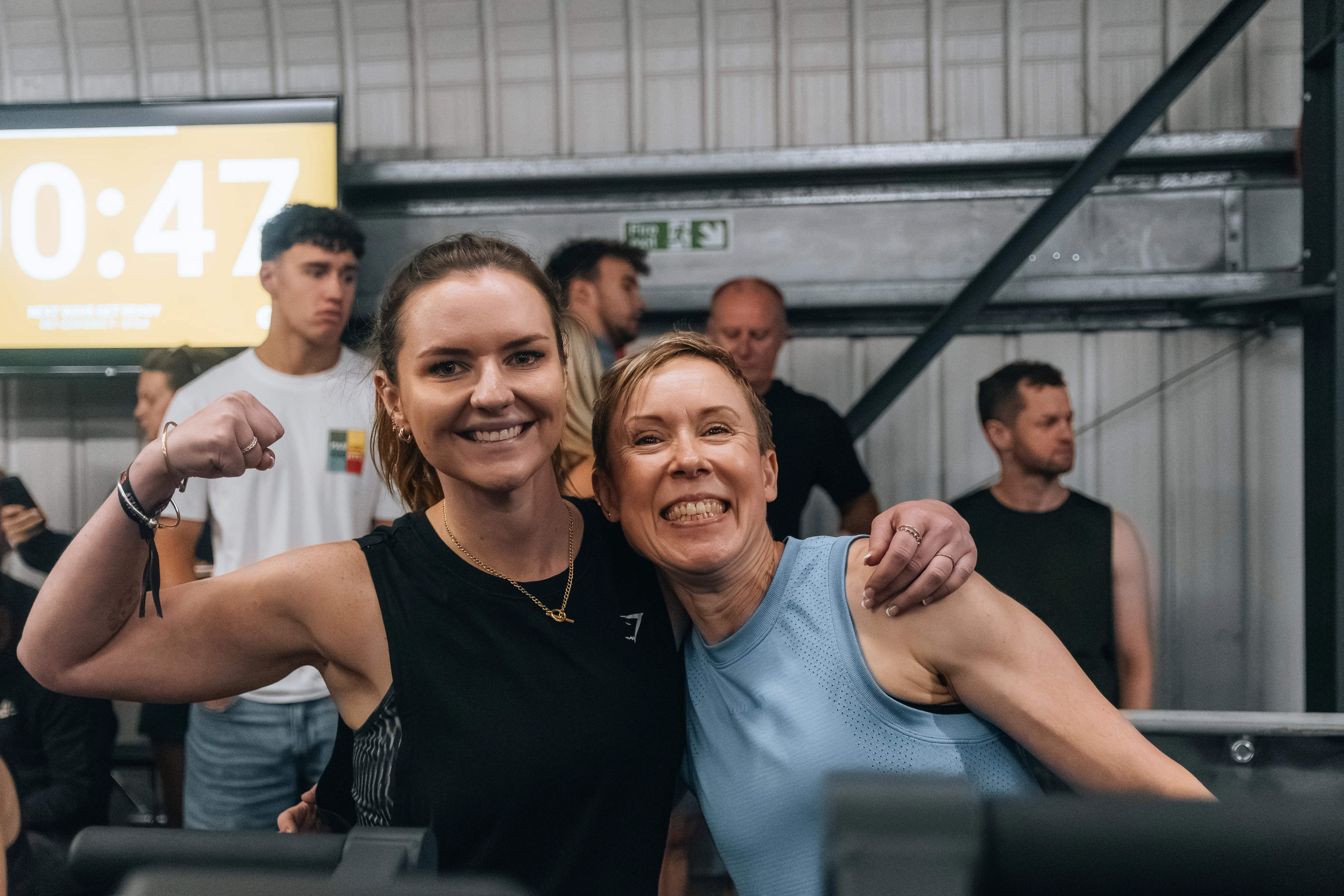 Two friends thumbs-up beside the competition timer between heats.