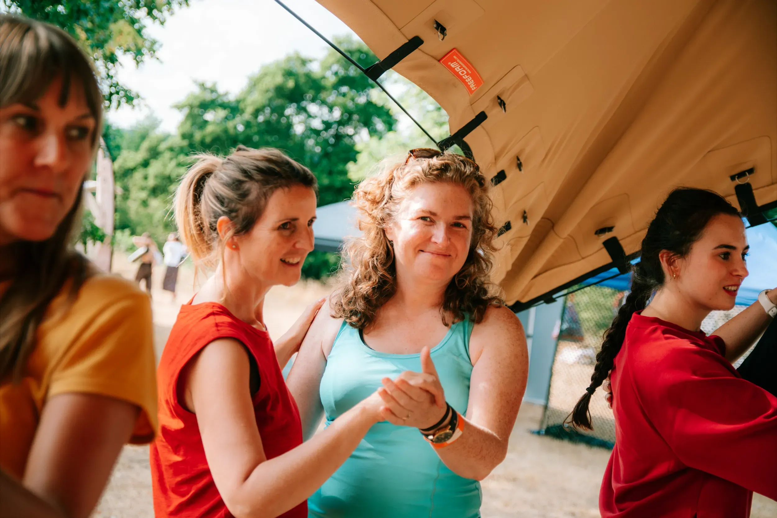 A row of festivalgoers clapping along mid-laugh under the marquee.