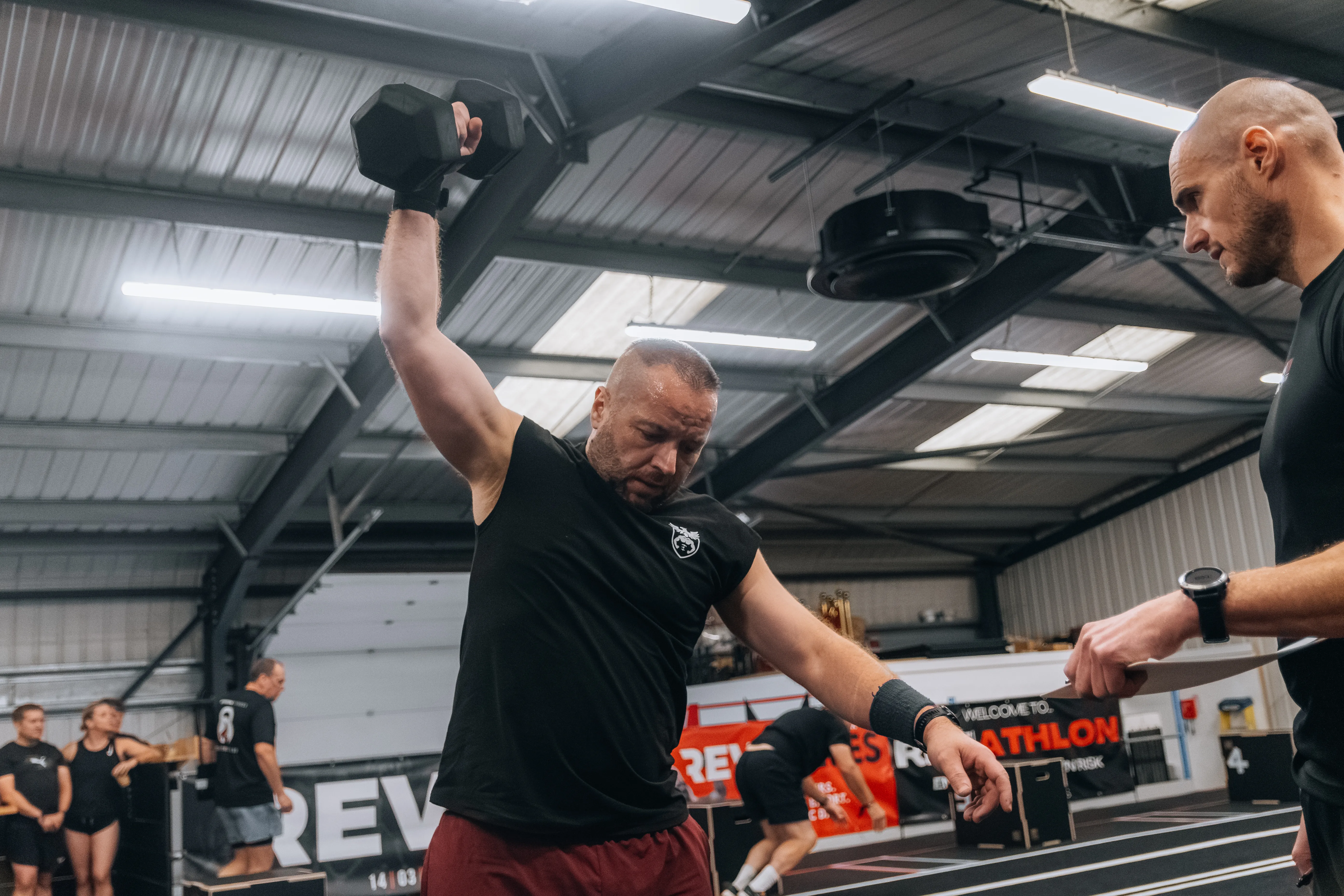 Two competitors working through dumbbell presses side by side.