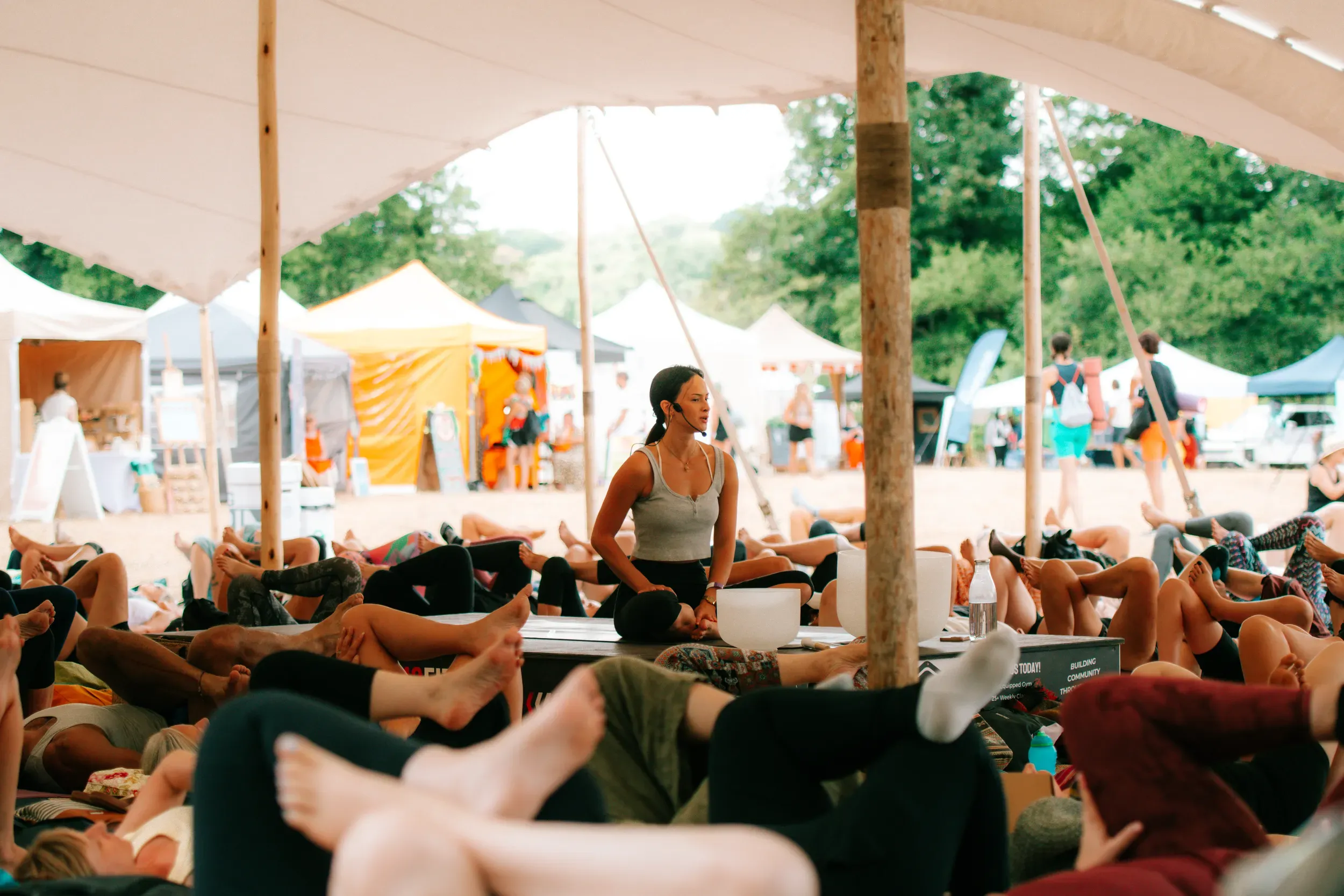 A sound bath under the big tent, the practitioner sat with her singing bowls while the class lies back on their mats.