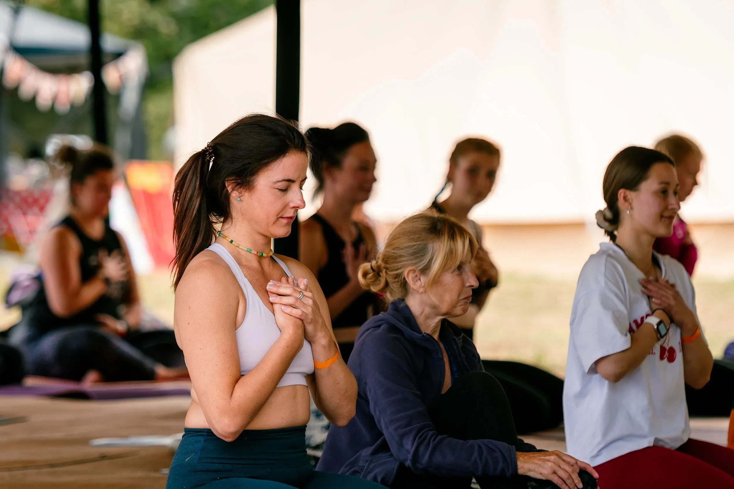 Women seated on mats, one resting her hands over her heart during a quiet moment.