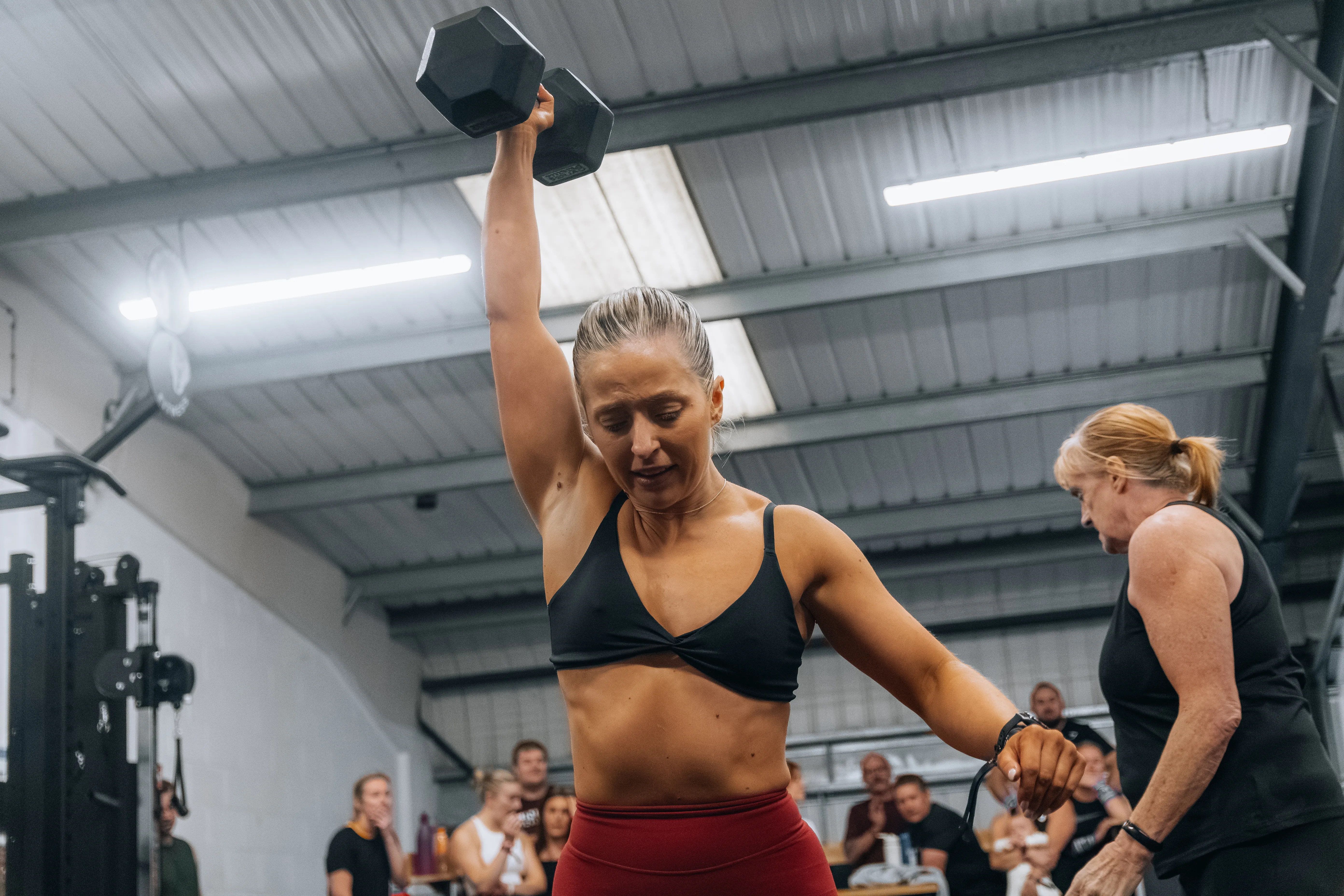 A competitor mid dumbbell snatch, weight overhead.