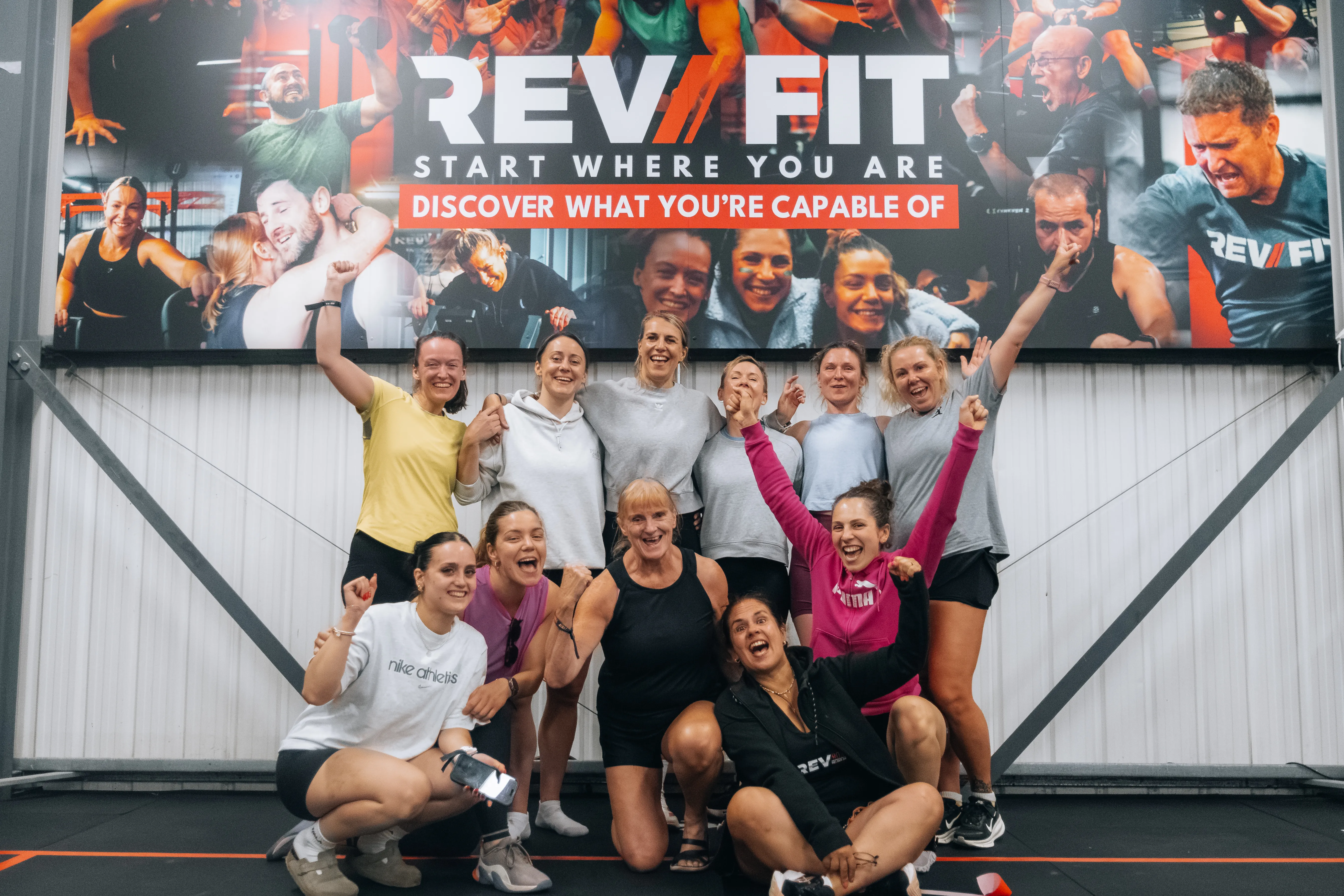 Competitors and crew celebrating together under the Rev Fit sign.