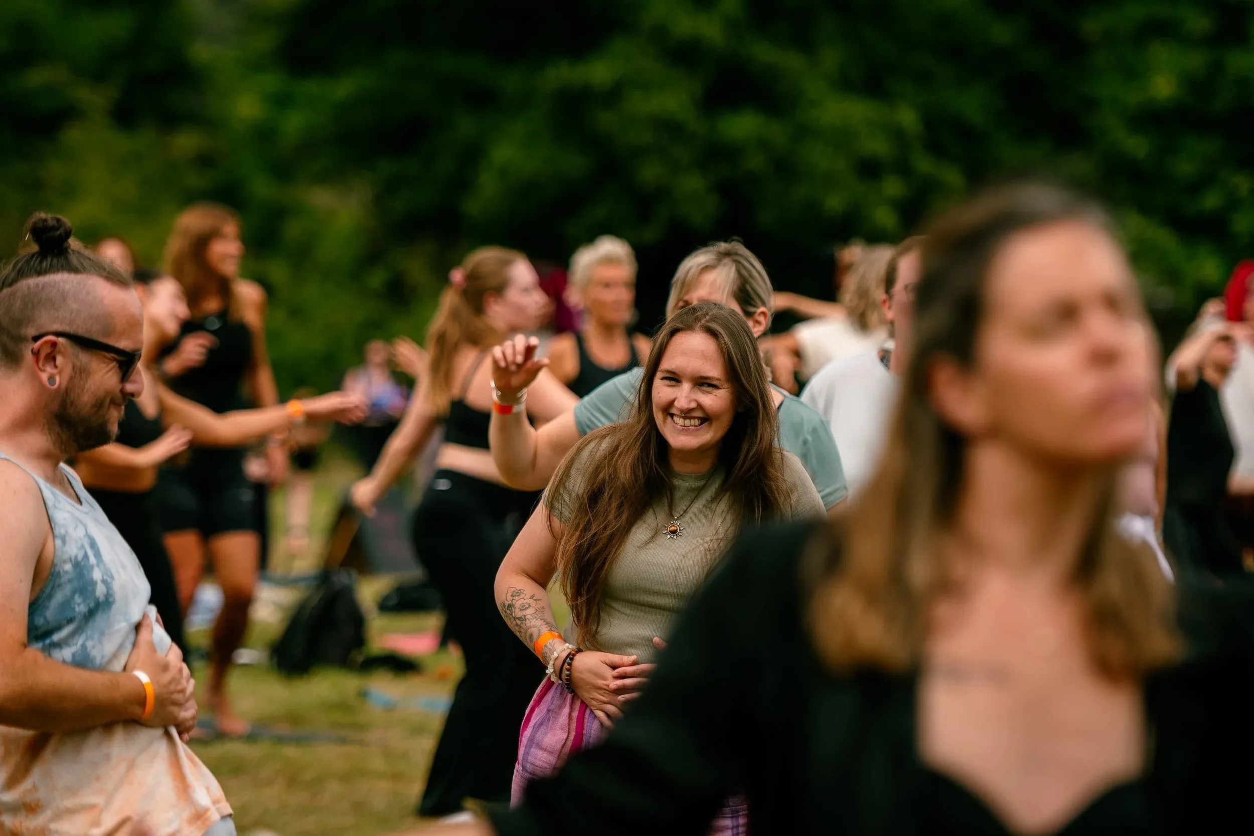 Dancers in motion outdoors, a smiling woman at the centre of the blur.